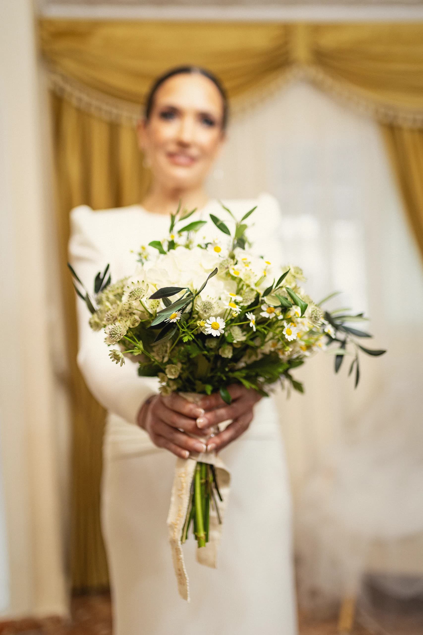 La novia con el ramo, de pie ante la puerta de la casa