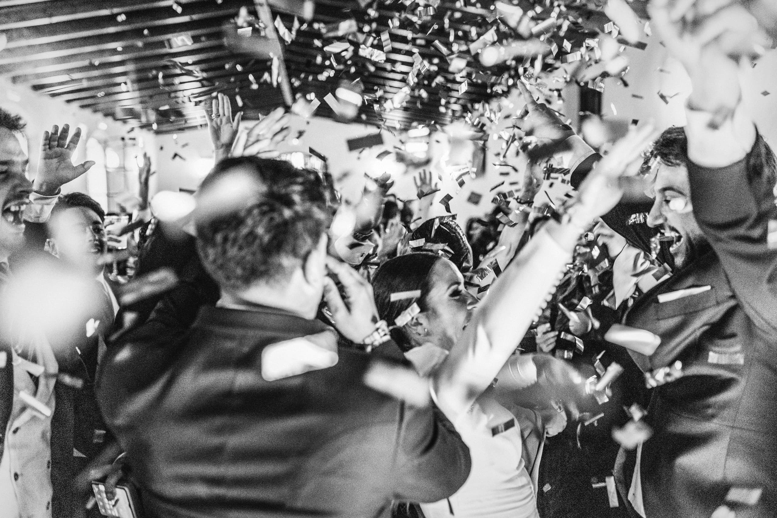 Los novios rodeados de invitados en plena fiesta, en blanco y negro