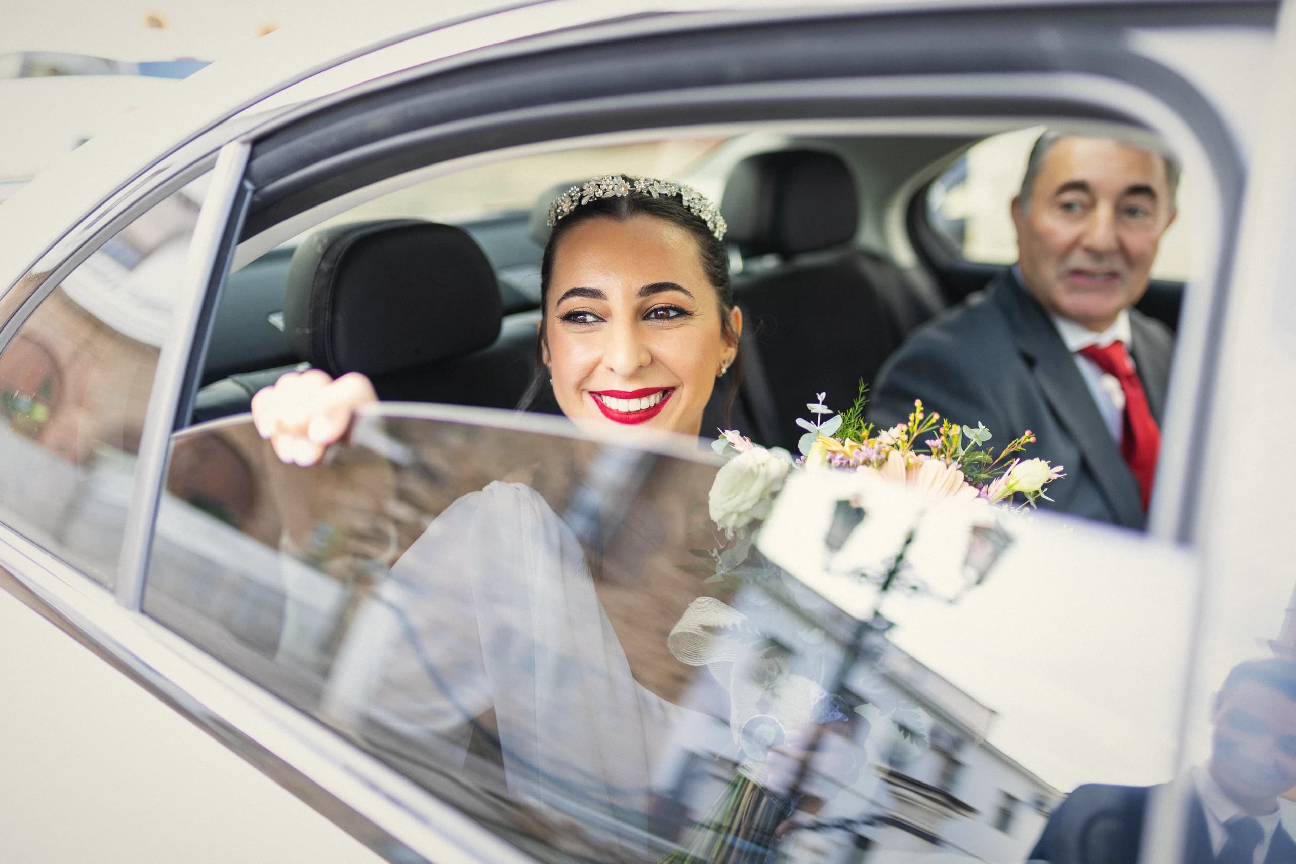 La novia sonriendo desde el coche junto a su padre