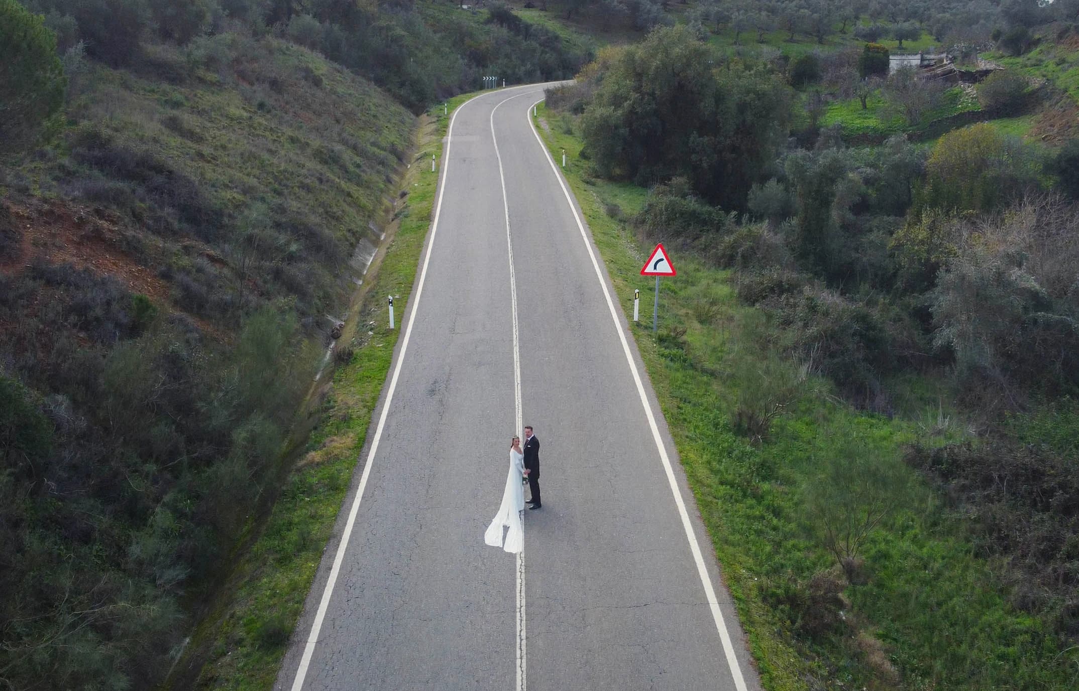 Vista aérea de la carretera con los novios en el centro de la curva