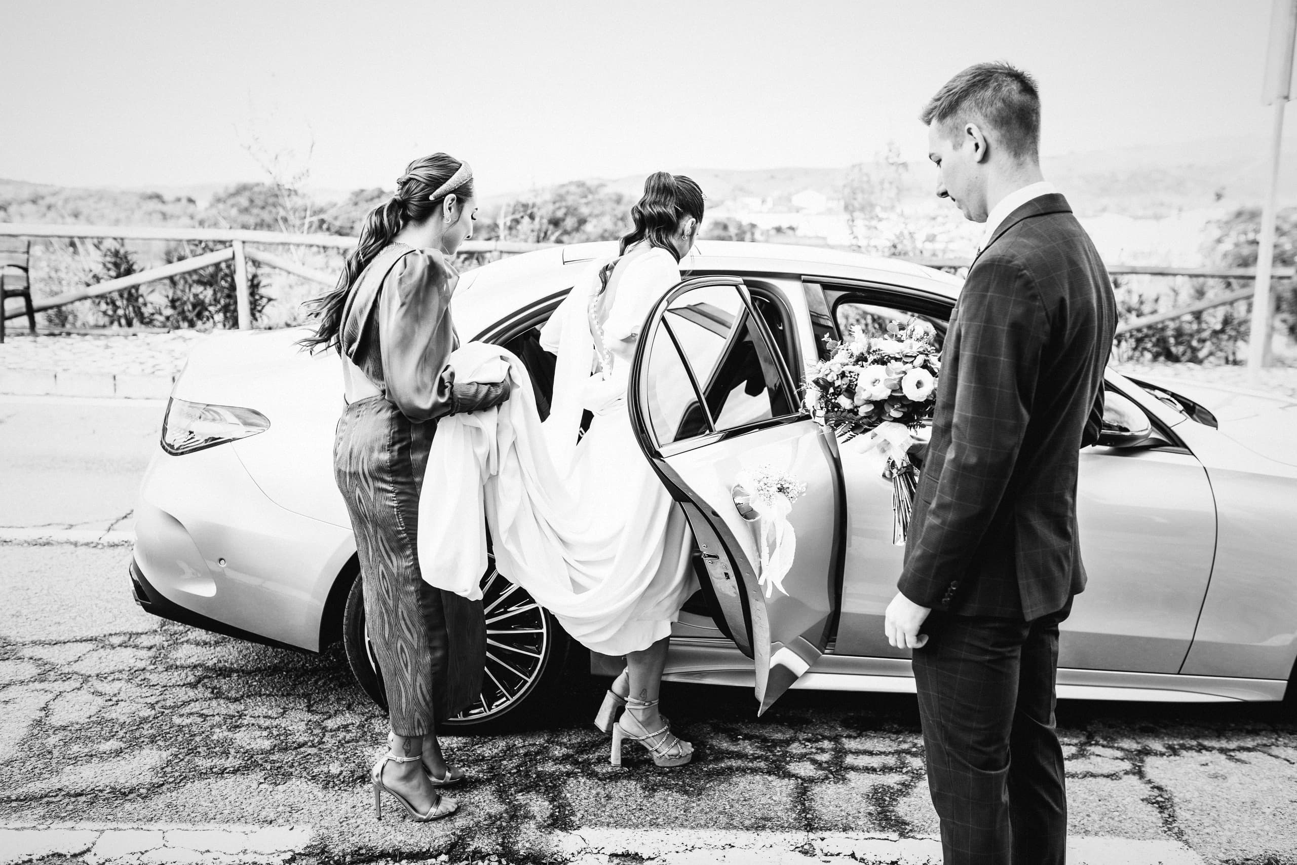 Los novios junto al coche en mitad del campo, en blanco y negro