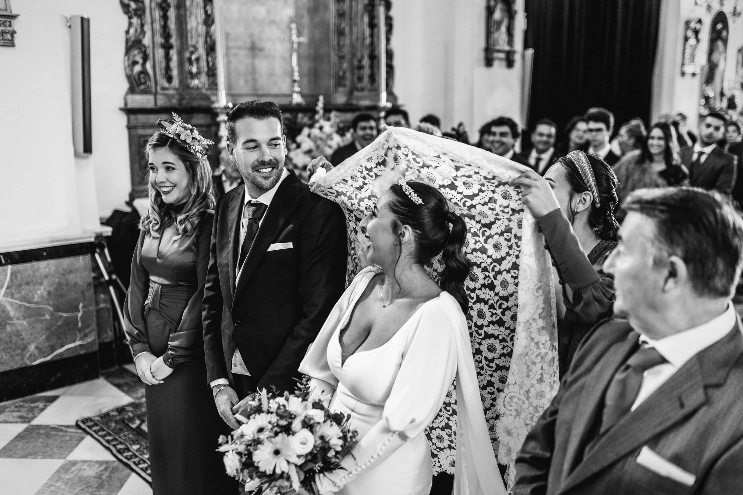 La novia con mantilla durante la ceremonia, en blanco y negro