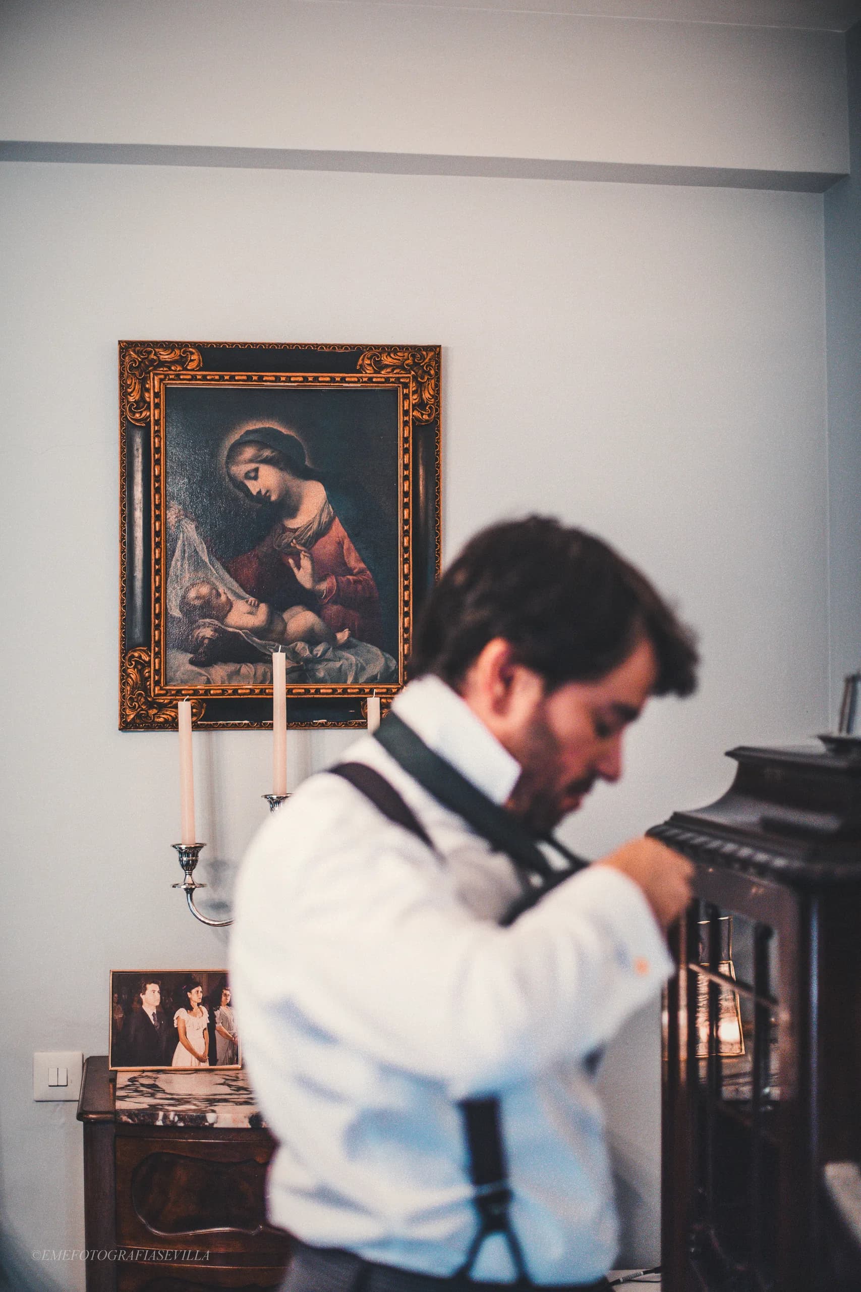 El novio ajustándose los tirantes junto a la cómoda