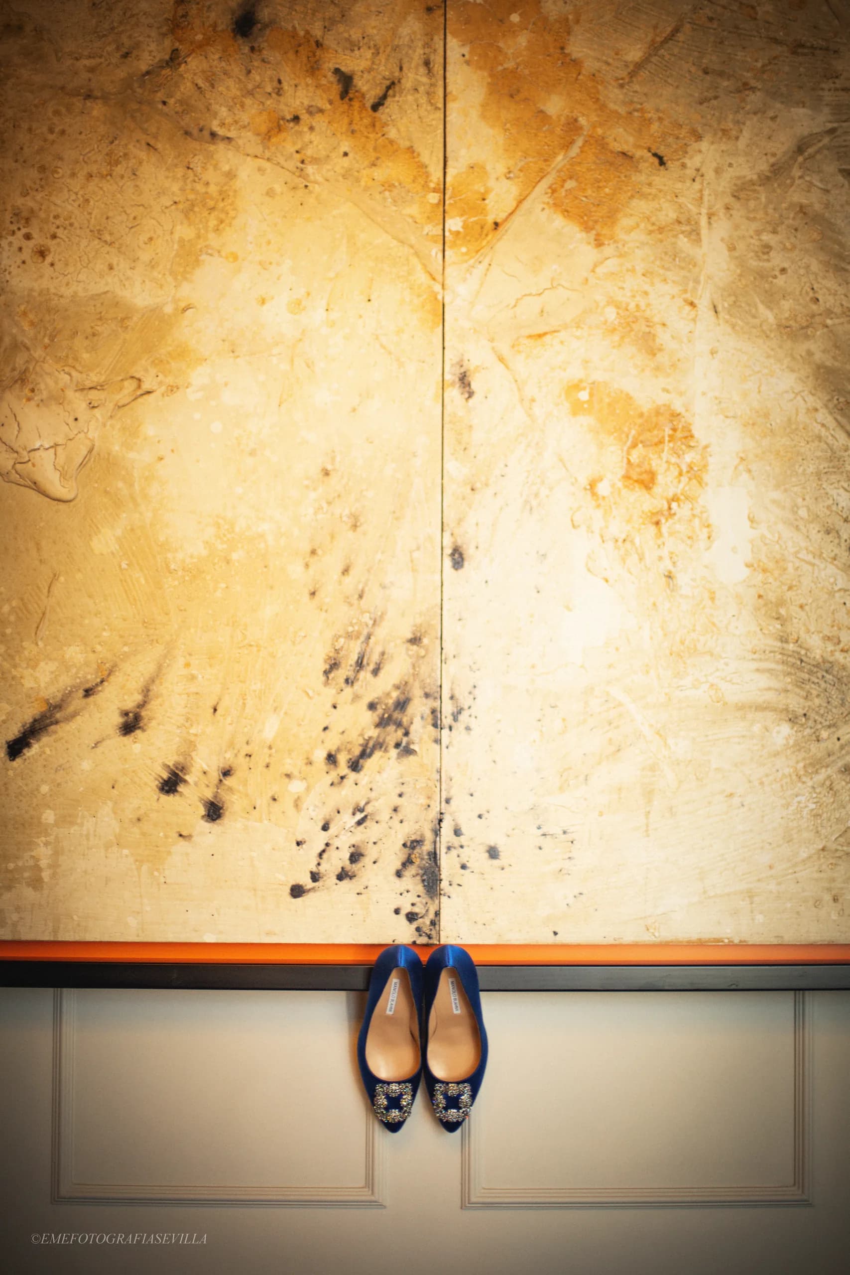 Los zapatos azules de la novia colgados de la pared dorada