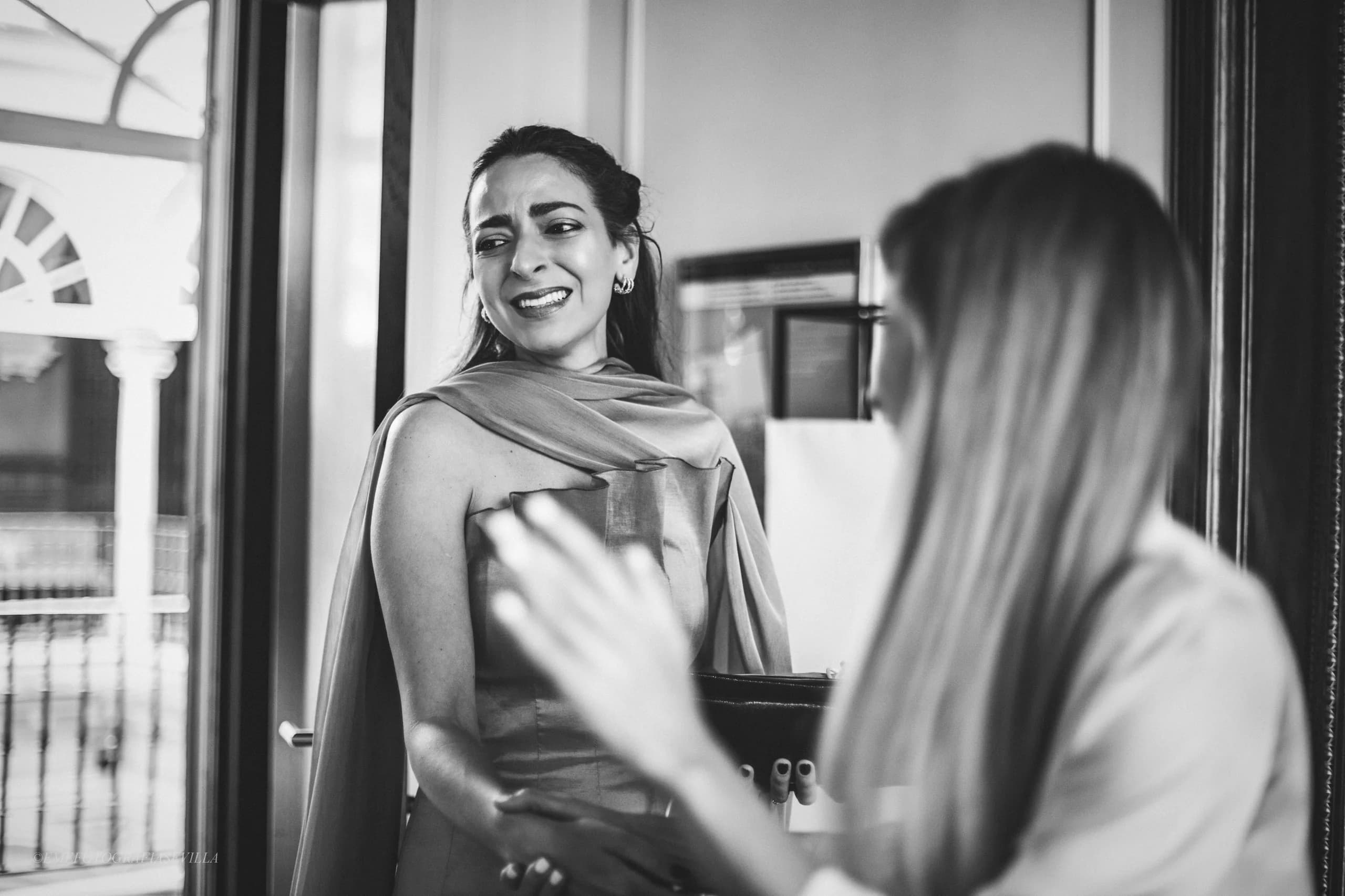 La novia abrazando a una invitada, en blanco y negro