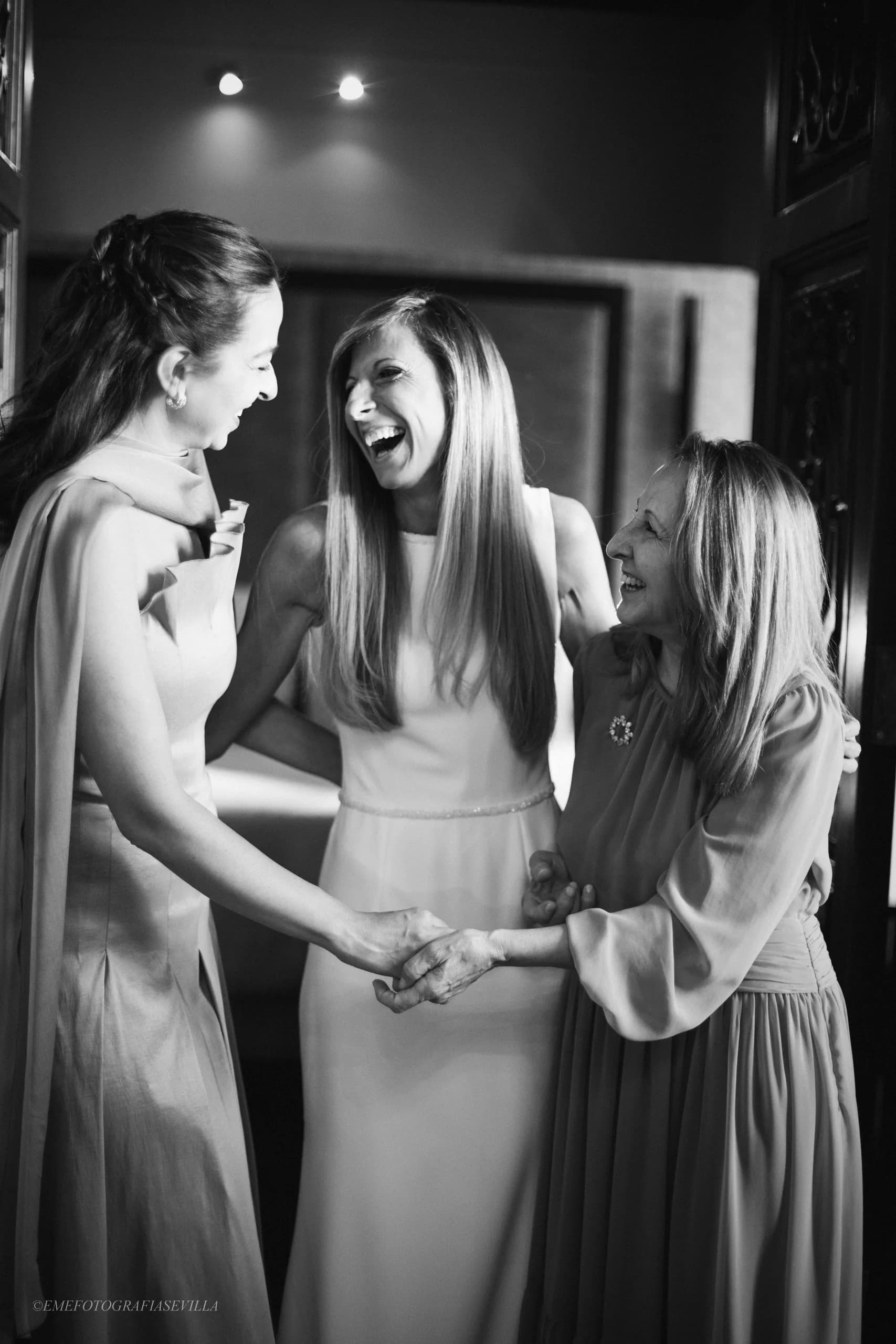 La novia riéndose con sus amigas antes de salir, en blanco y negro