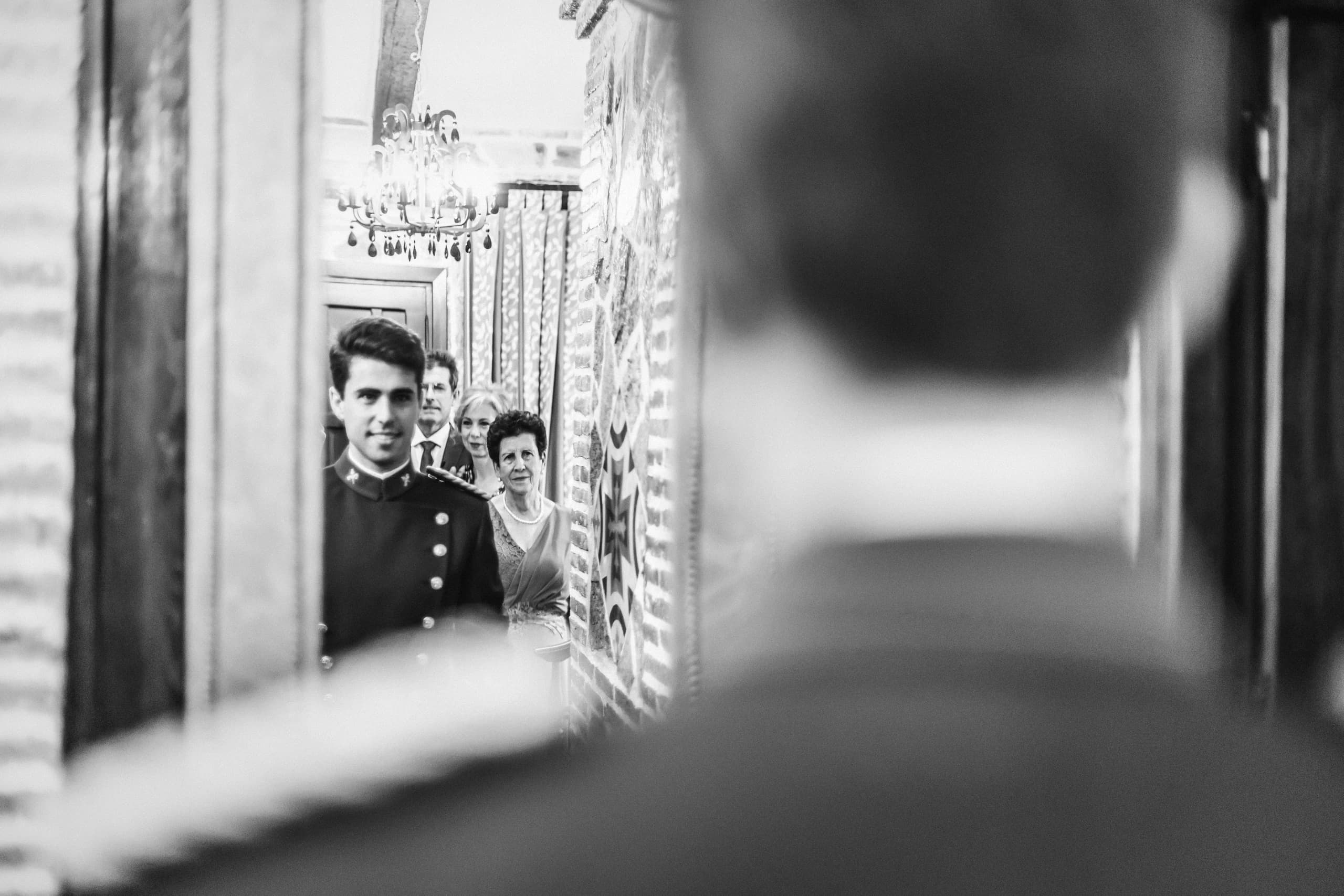 El novio de uniforme reflejado en el espejo mientras se viste, en blanco y negro