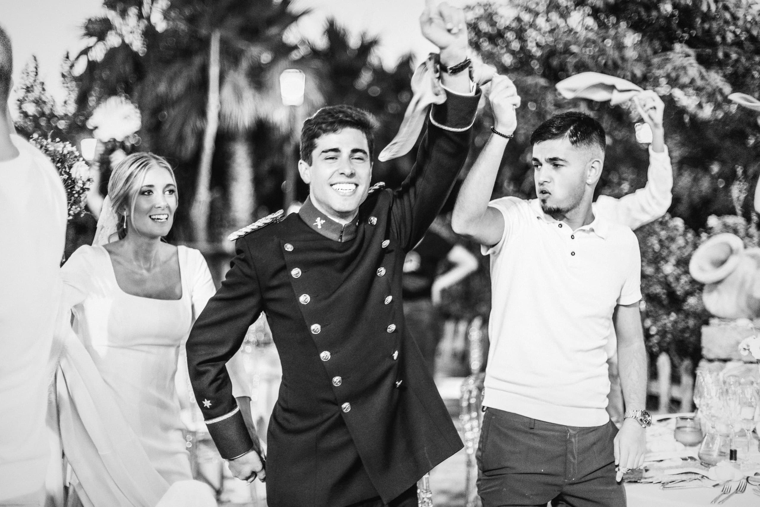 Los novios riendo entre amigos, en blanco y negro