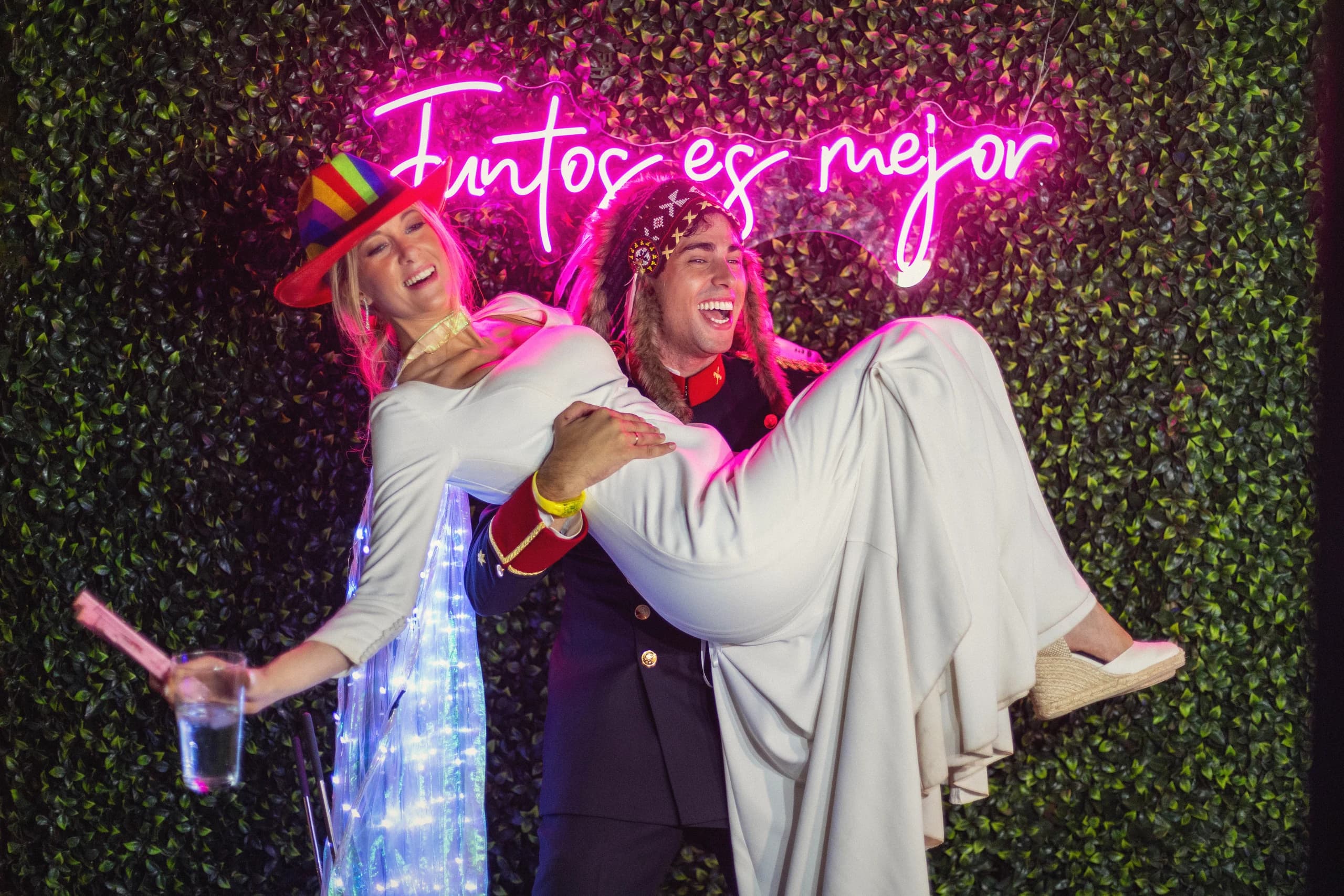 El novio con la novia en brazos bajo el neón