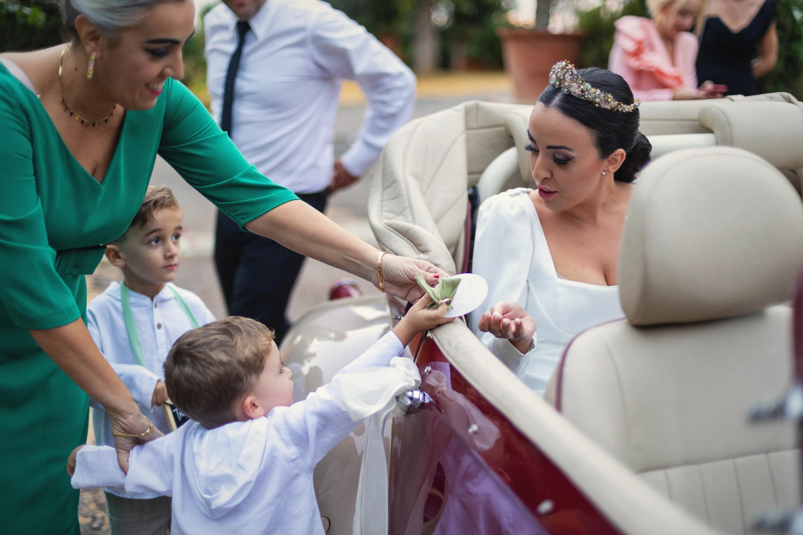 La novia llegando en el descapotable con la familia alrededor