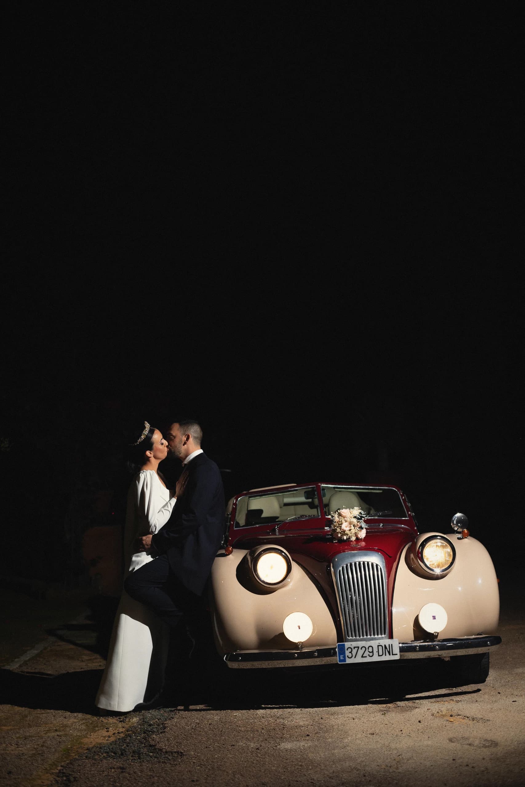 Beso junto al coche clásico de noche