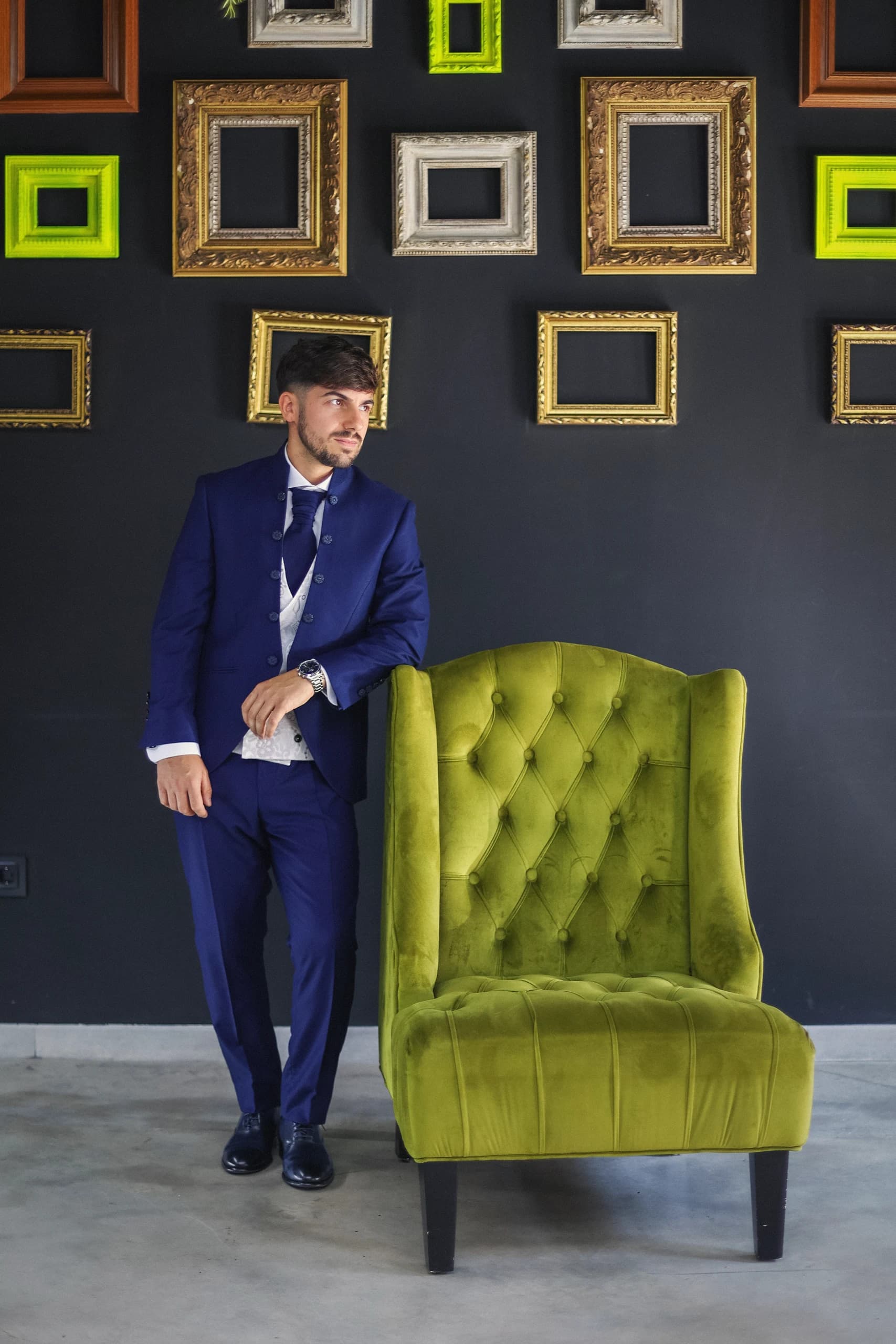 El novio de pie junto al sillón verde, en la sala de los cuadros