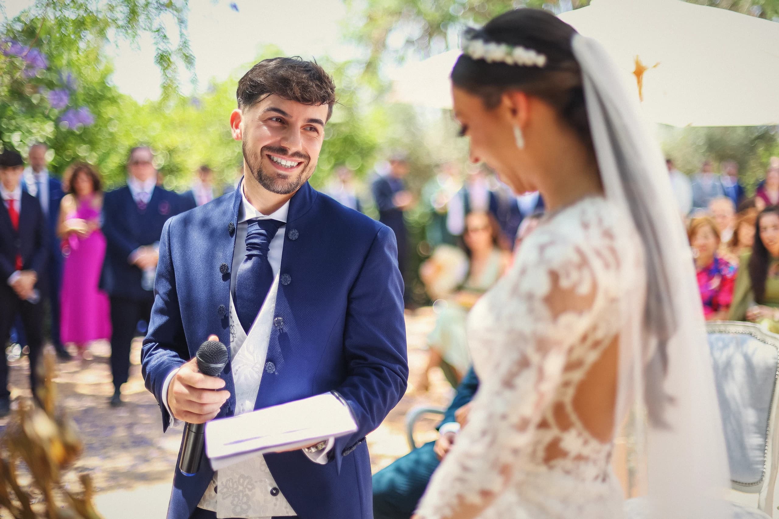 El novio leyendo sus votos frente a la novia, entre los invitados