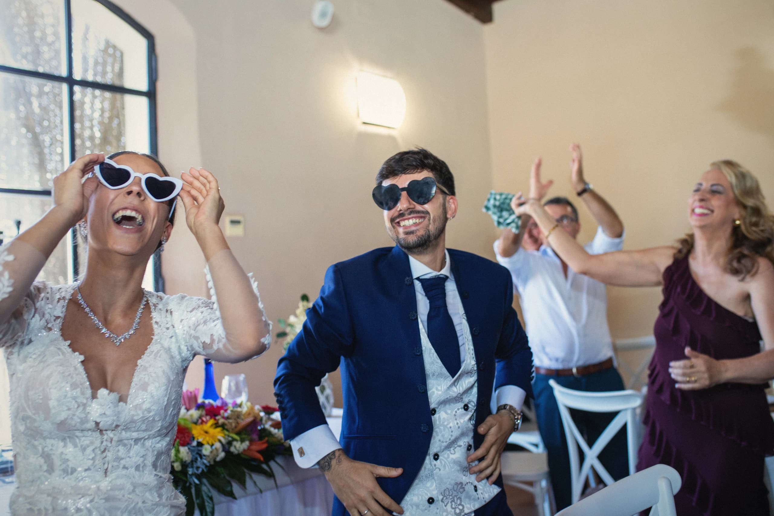 Los novios con gafas de sol y los invitados brindando