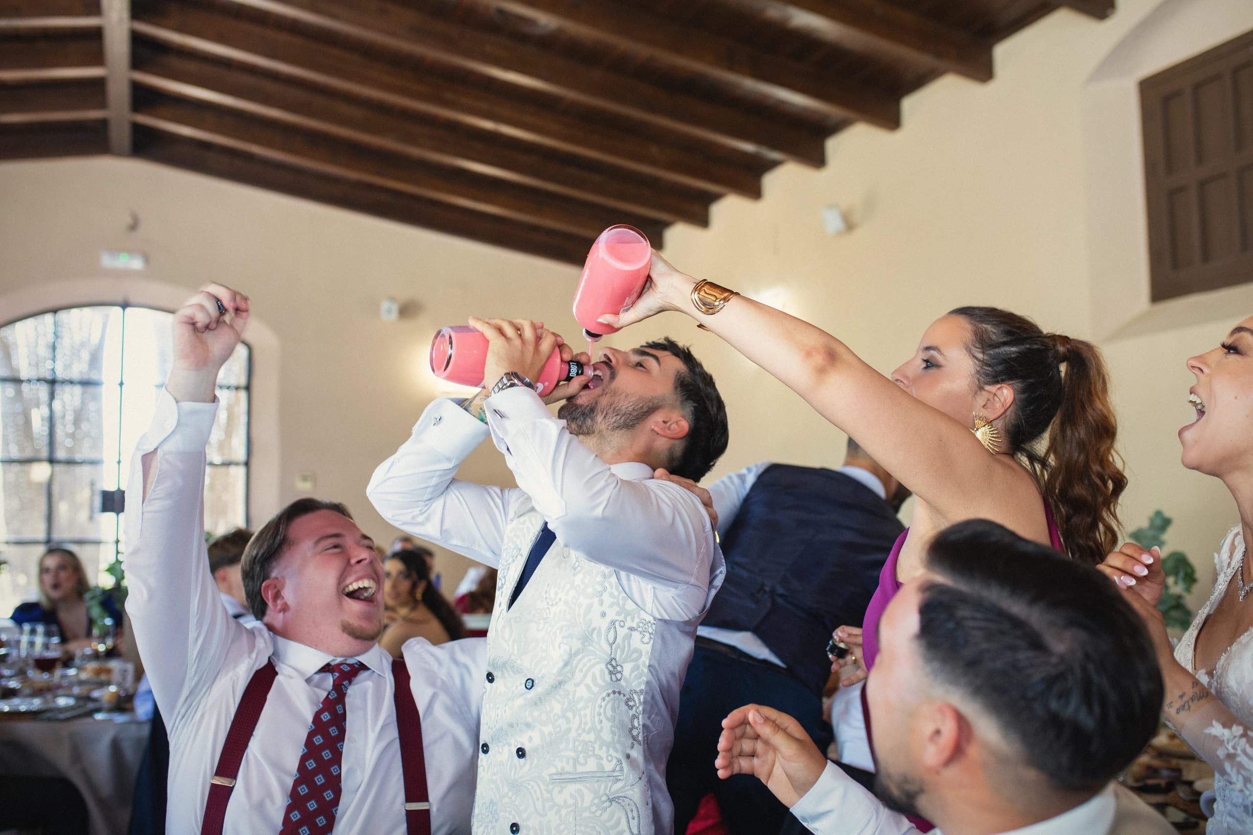 Invitados bebiendo de la bota y riéndose en plena fiesta