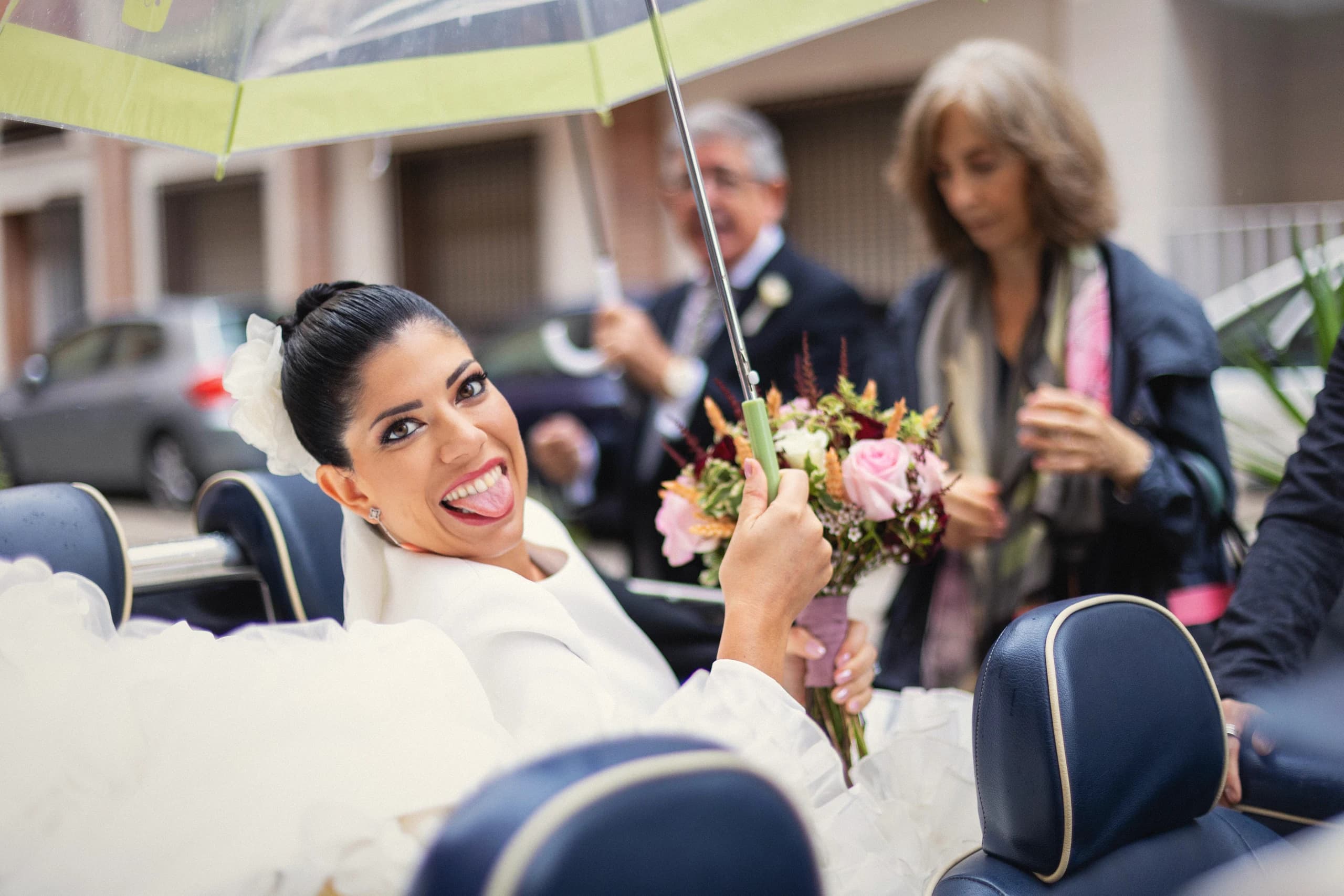 La novia sonriendo desde el coche bajo la lluvia
