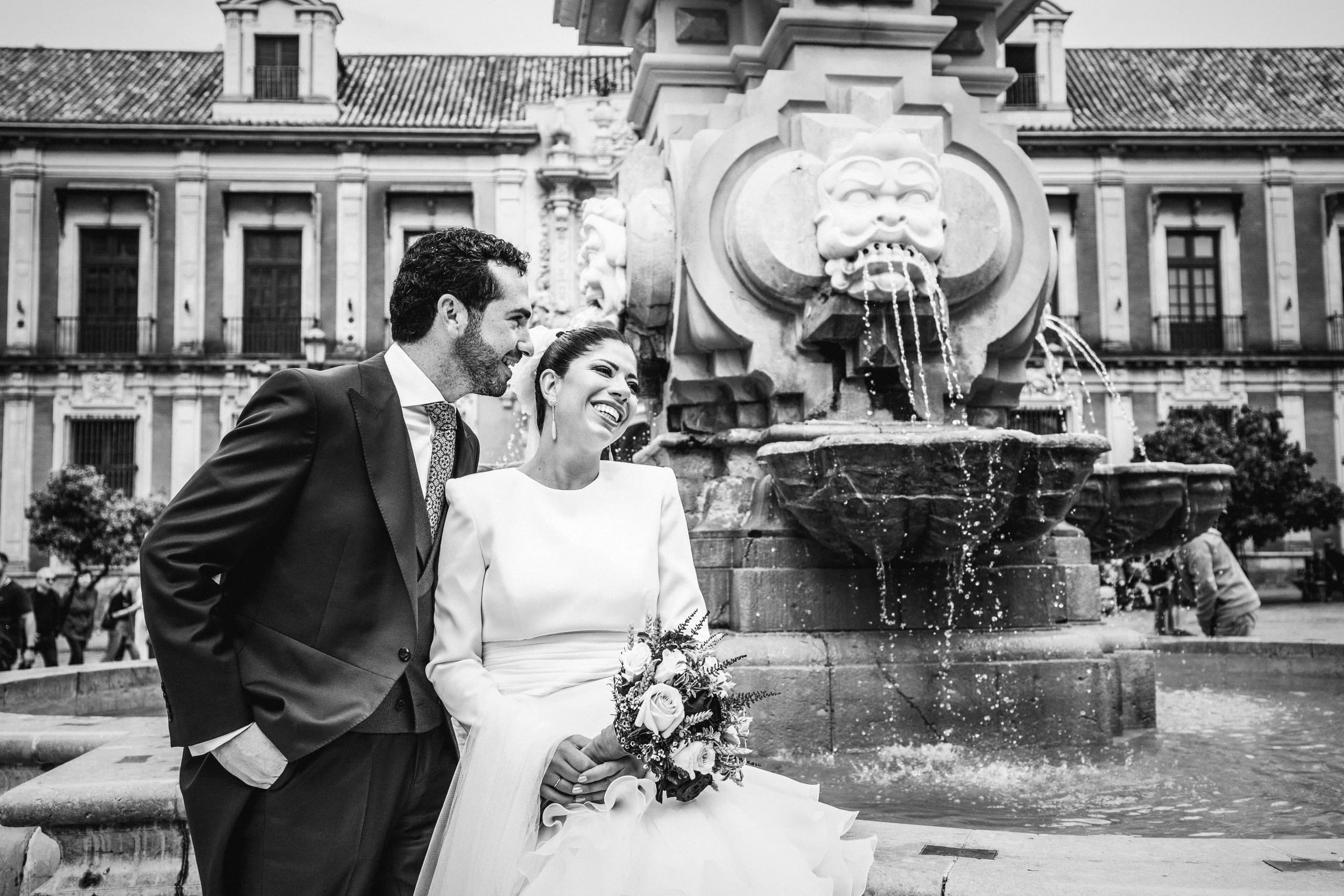 Los novios junto a la fuente de la plaza, en blanco y negro
