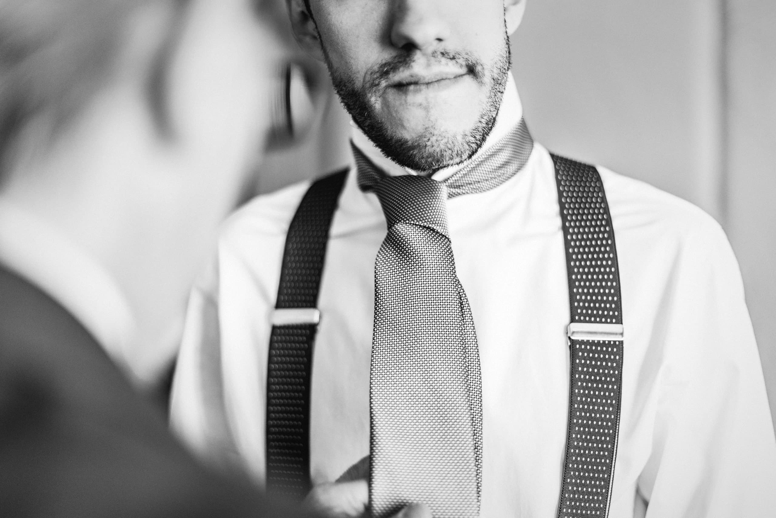 El novio con los tirantes y la corbata a medio hacer, en blanco y negro