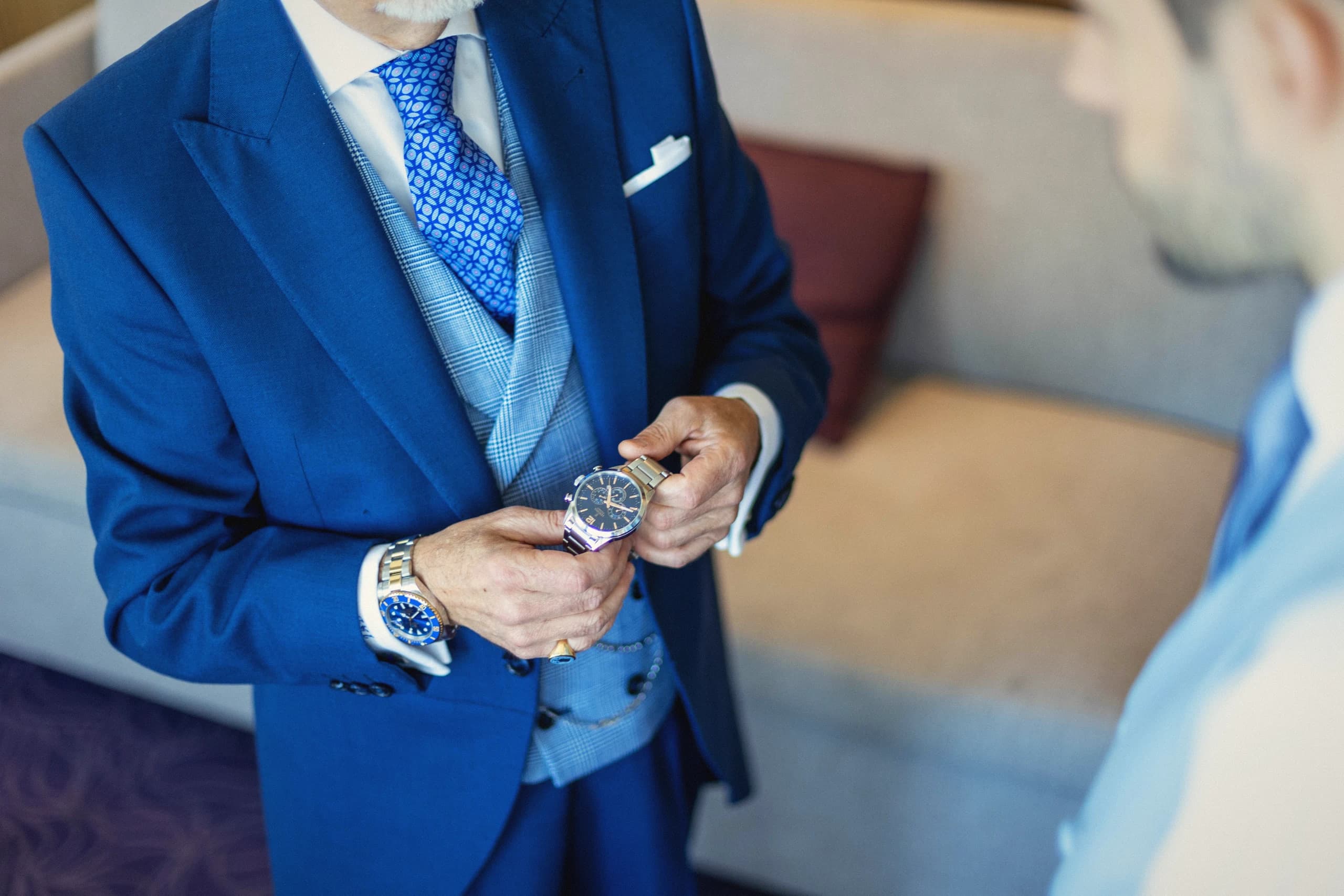 El novio abrochándose el reloj, con el traje azul