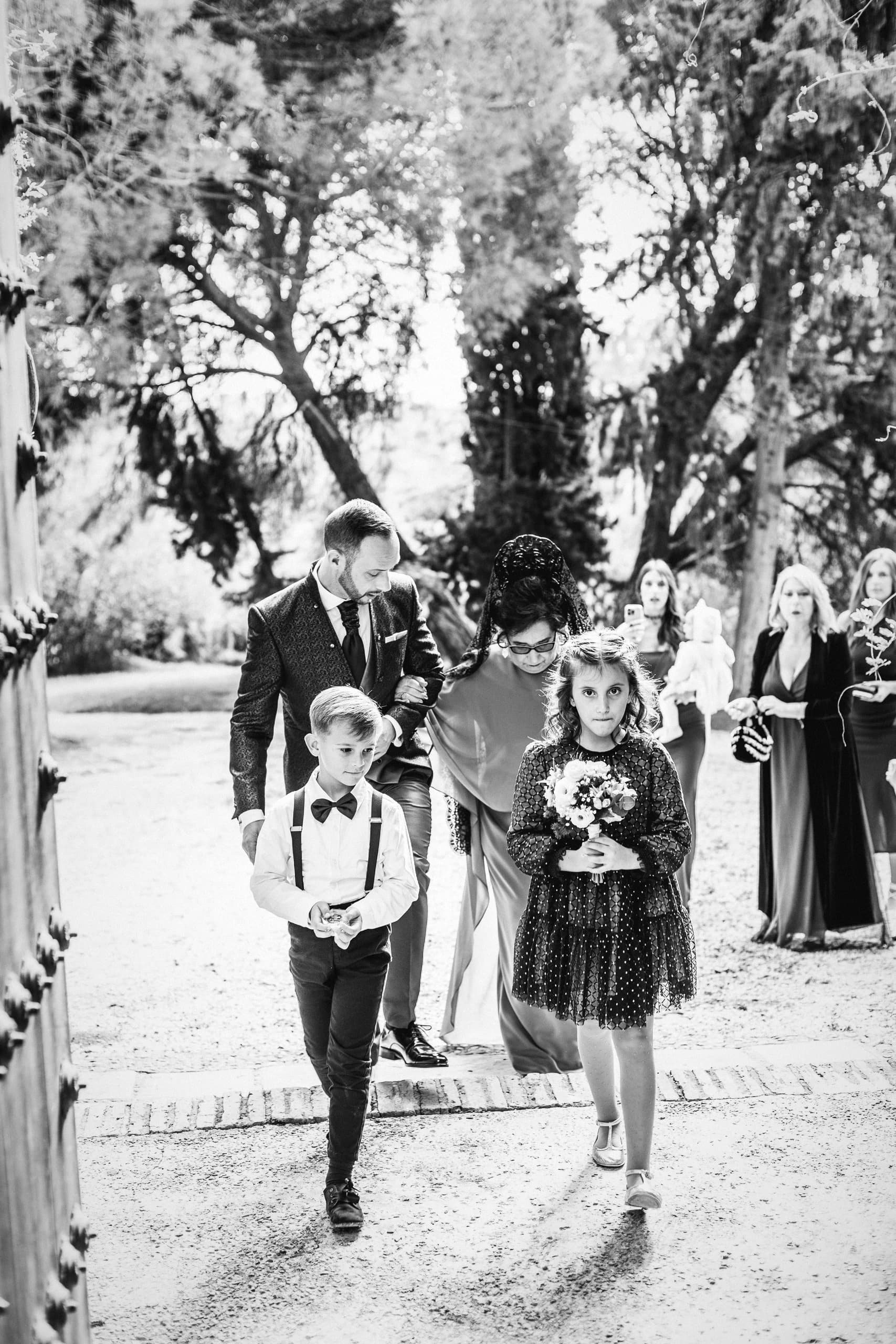 Los pajes cruzando el jardín hacia la ceremonia, en blanco y negro