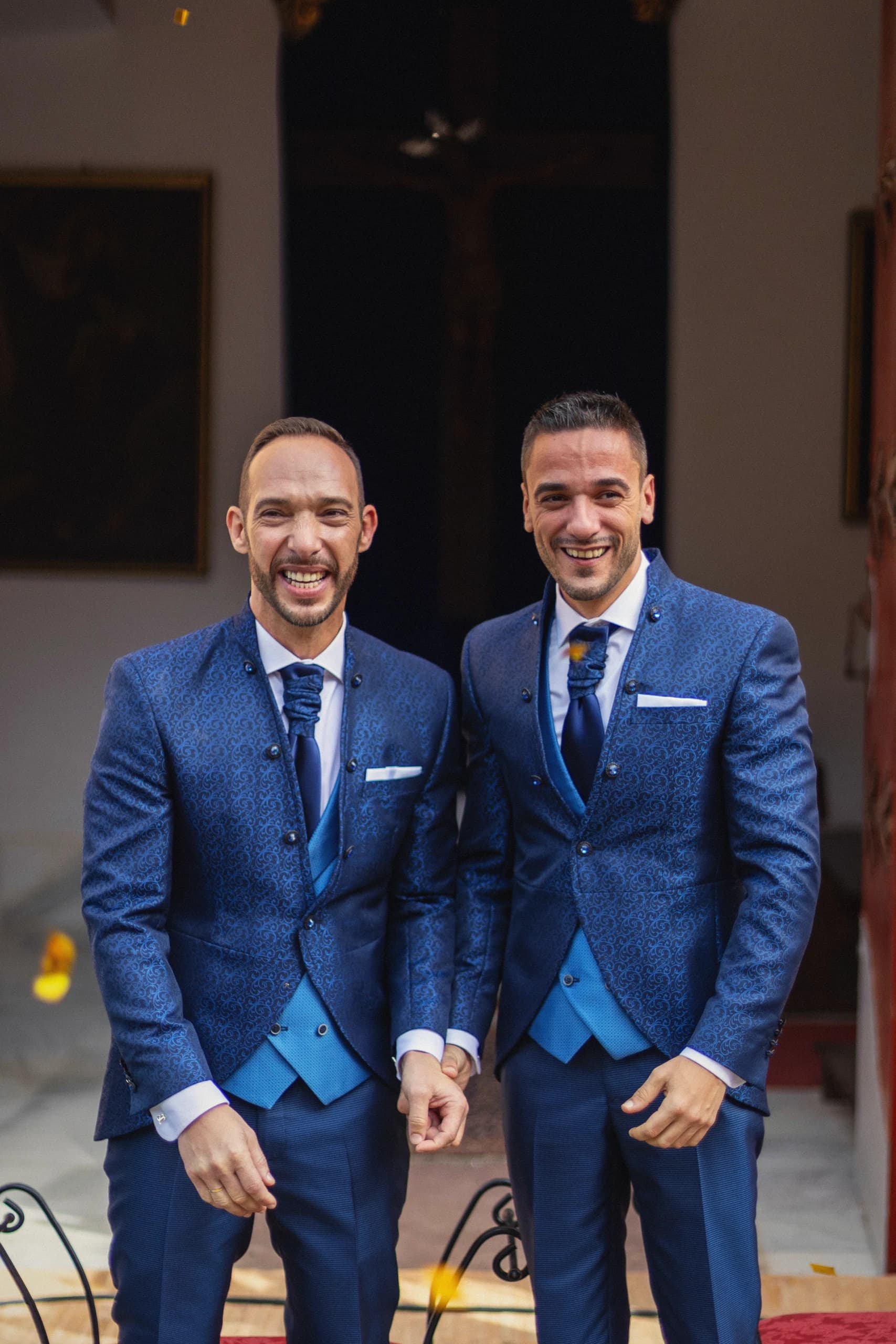 Los novios riendo bajo la lluvia de pétalos