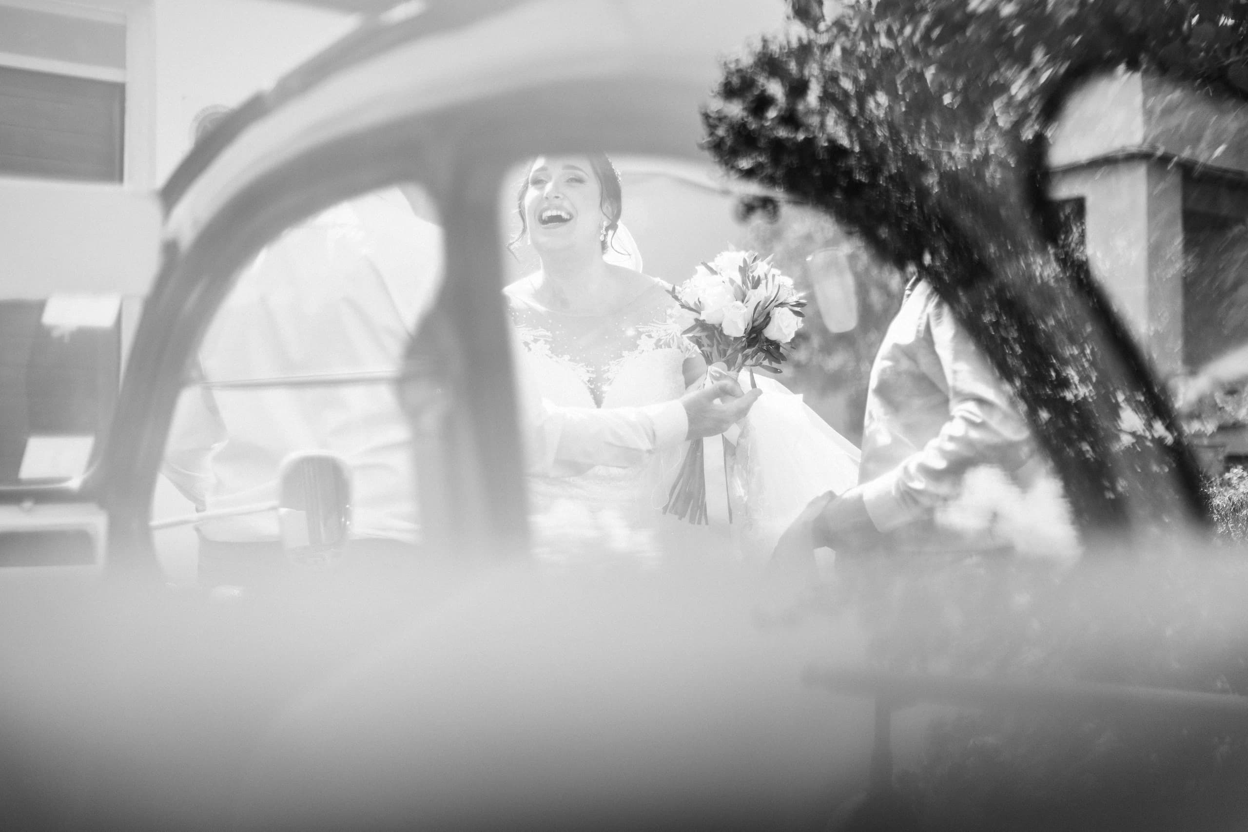 La novia bajo el velo llegando en el coche clásico, en blanco y negro