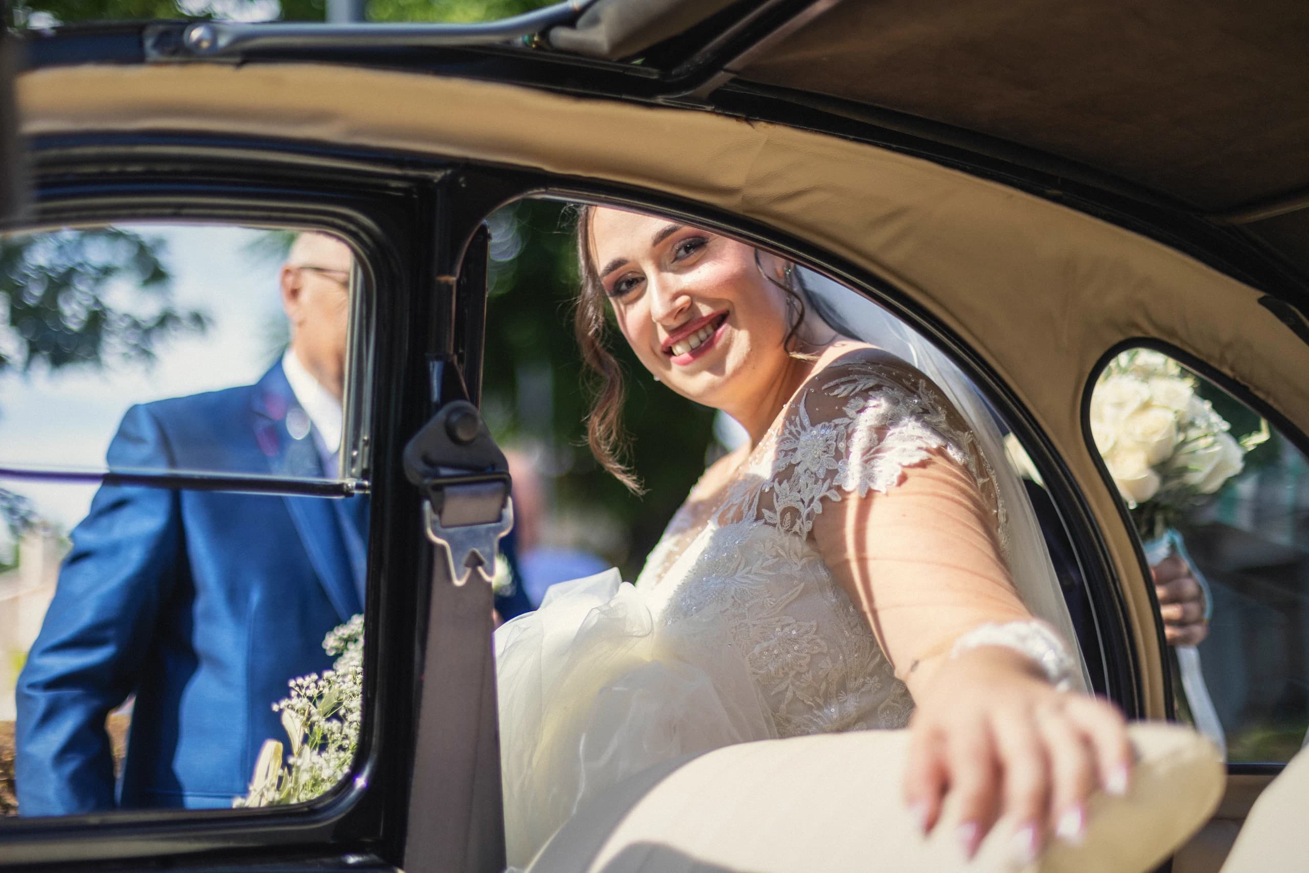 La novia saludando desde el coche clásico con el ramo