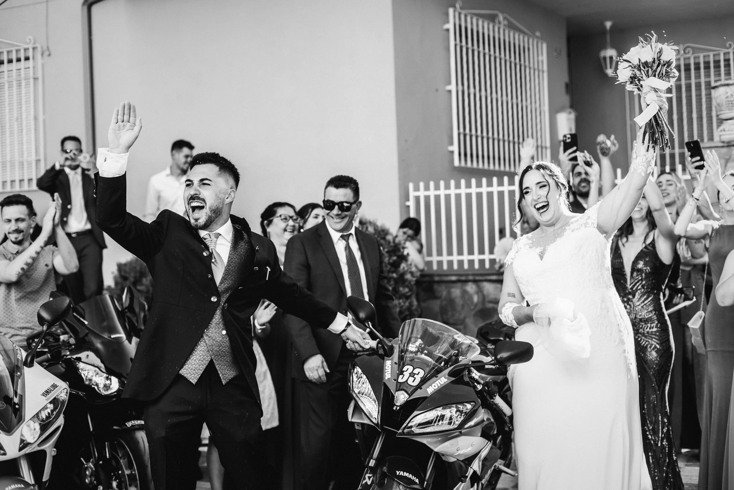 Los invitados celebrando con las motos a la puerta, en blanco y negro