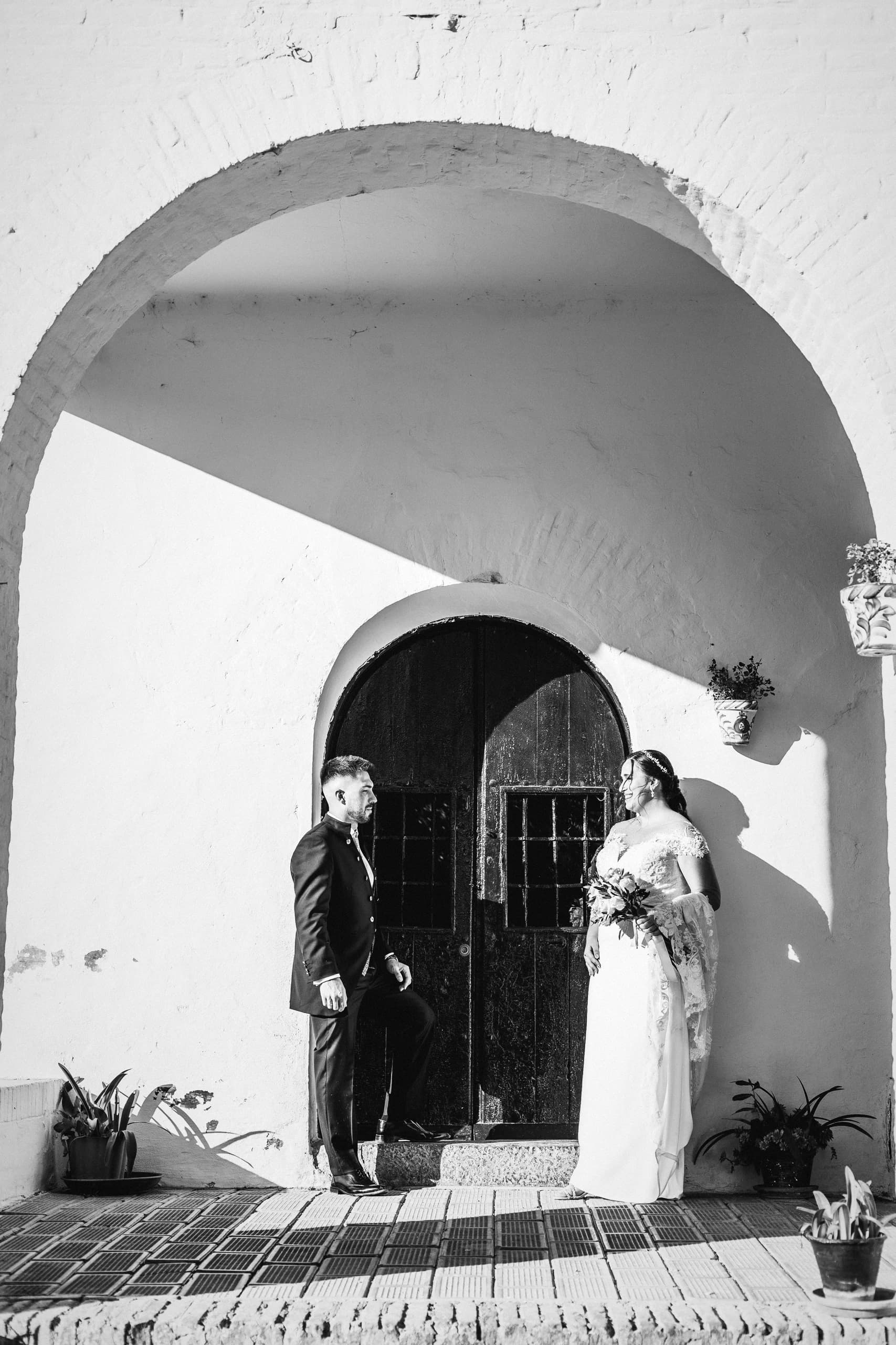 Los novios bajo el arco blanco de la ermita, en blanco y negro