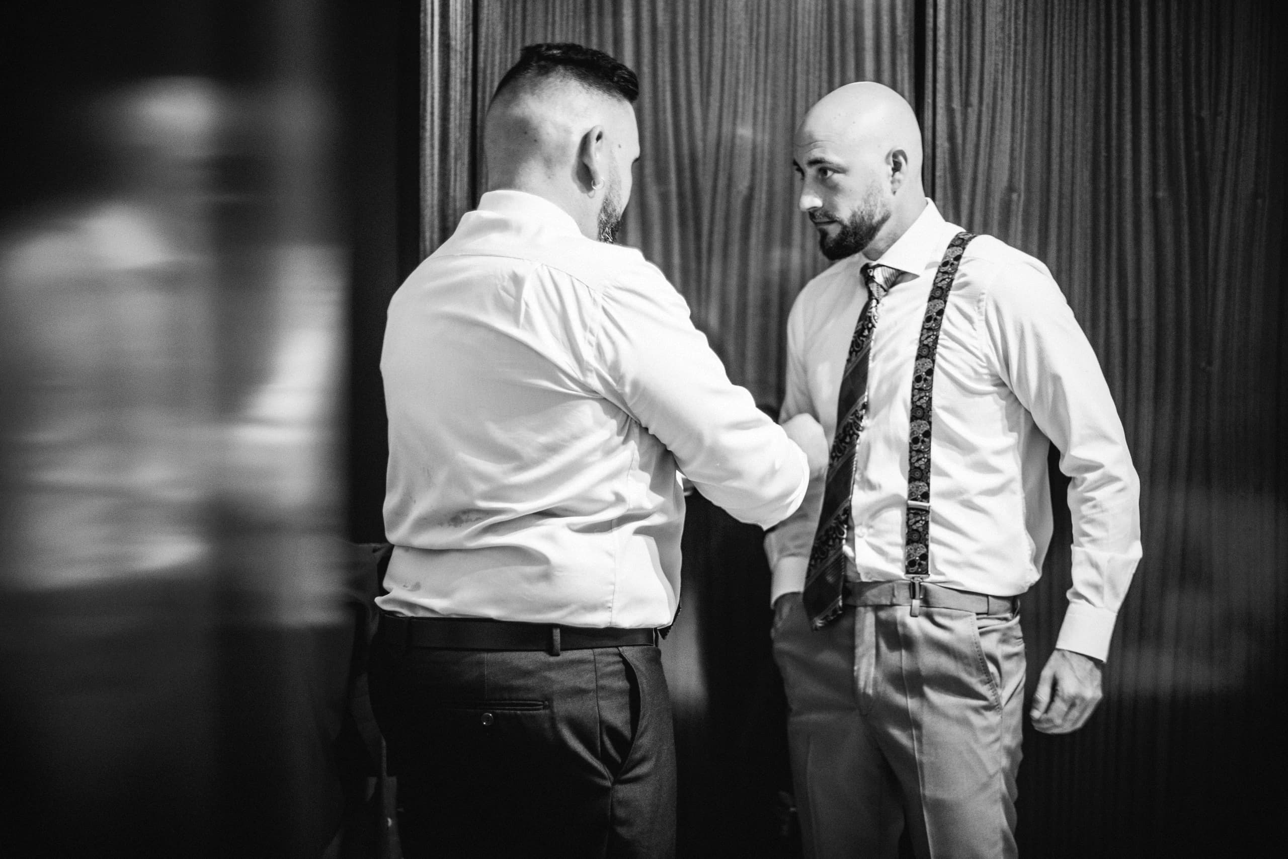 El novio ajustándose los tirantes, en blanco y negro