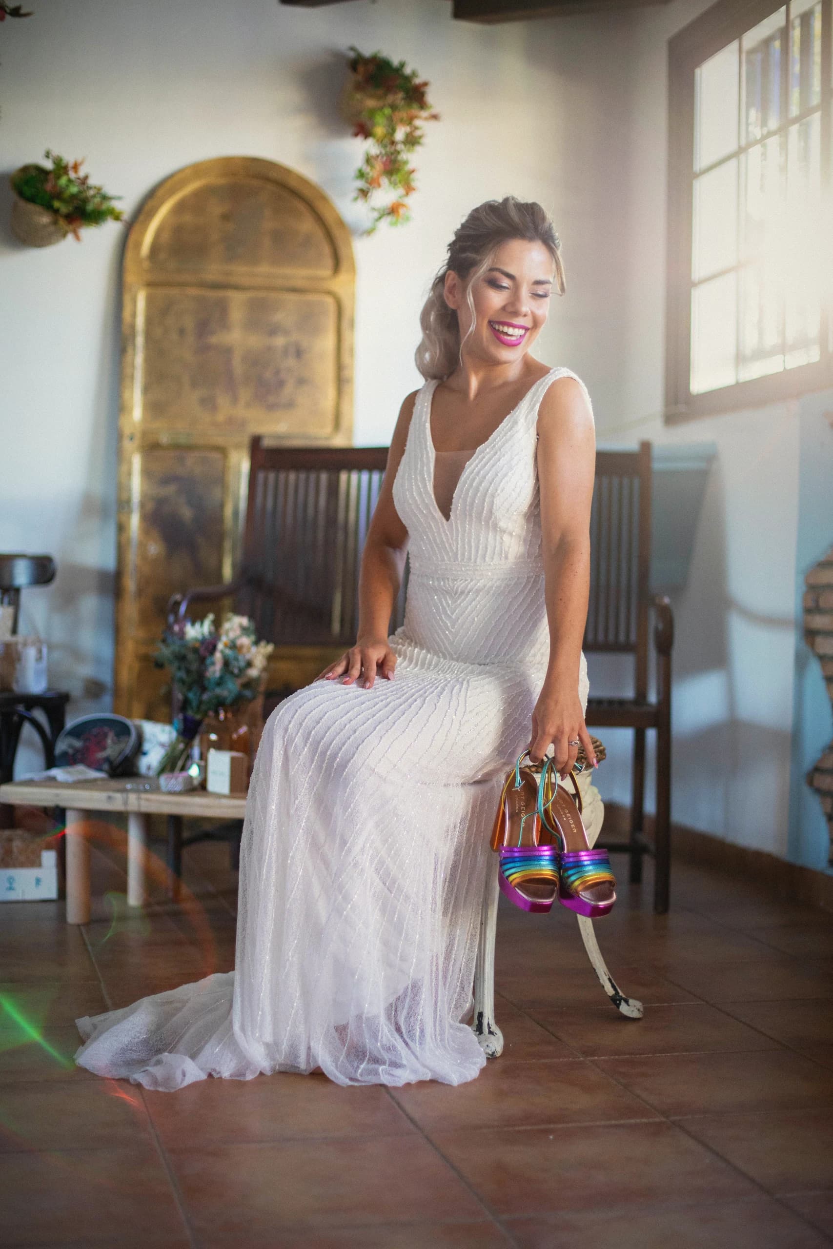 La novia sentada con los zapatos en la mano