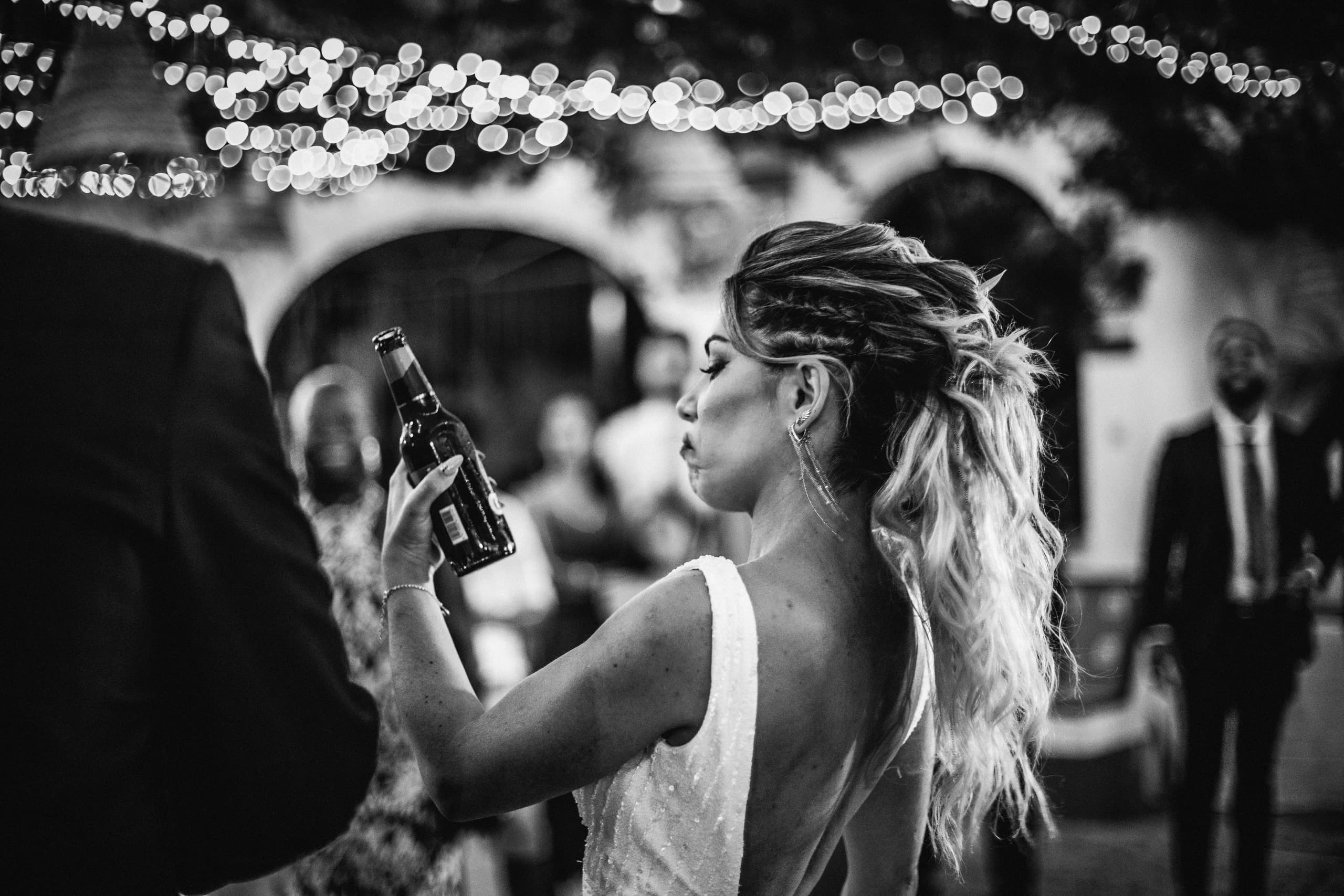La novia con una cerveza en la fiesta, en blanco y negro