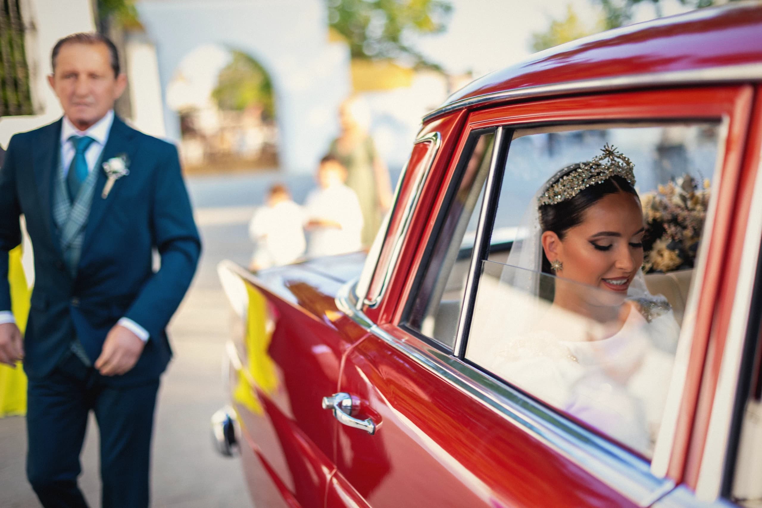 La novia llegando en un coche clásico rojo junto a su padre