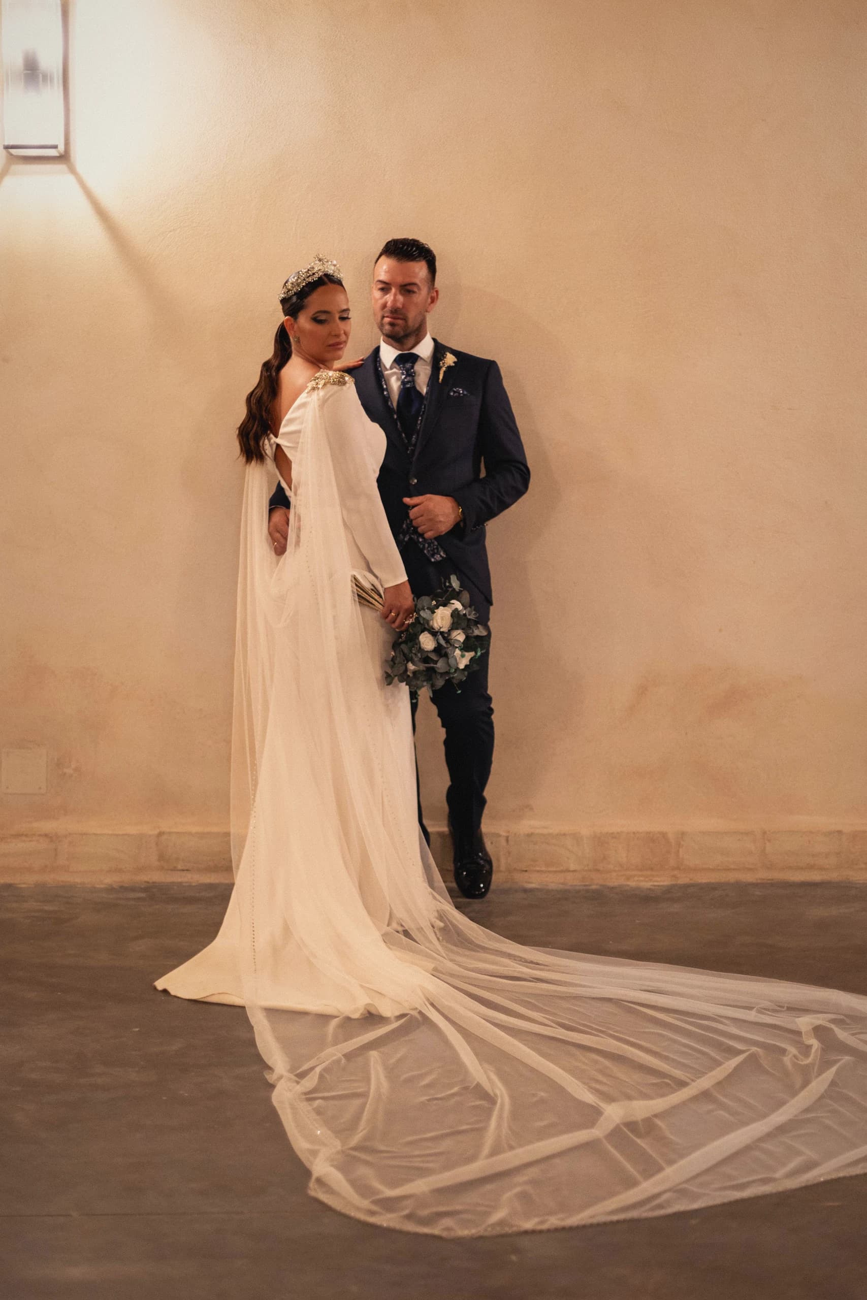 Los novios abrazados con la cola del vestido extendida sobre el suelo