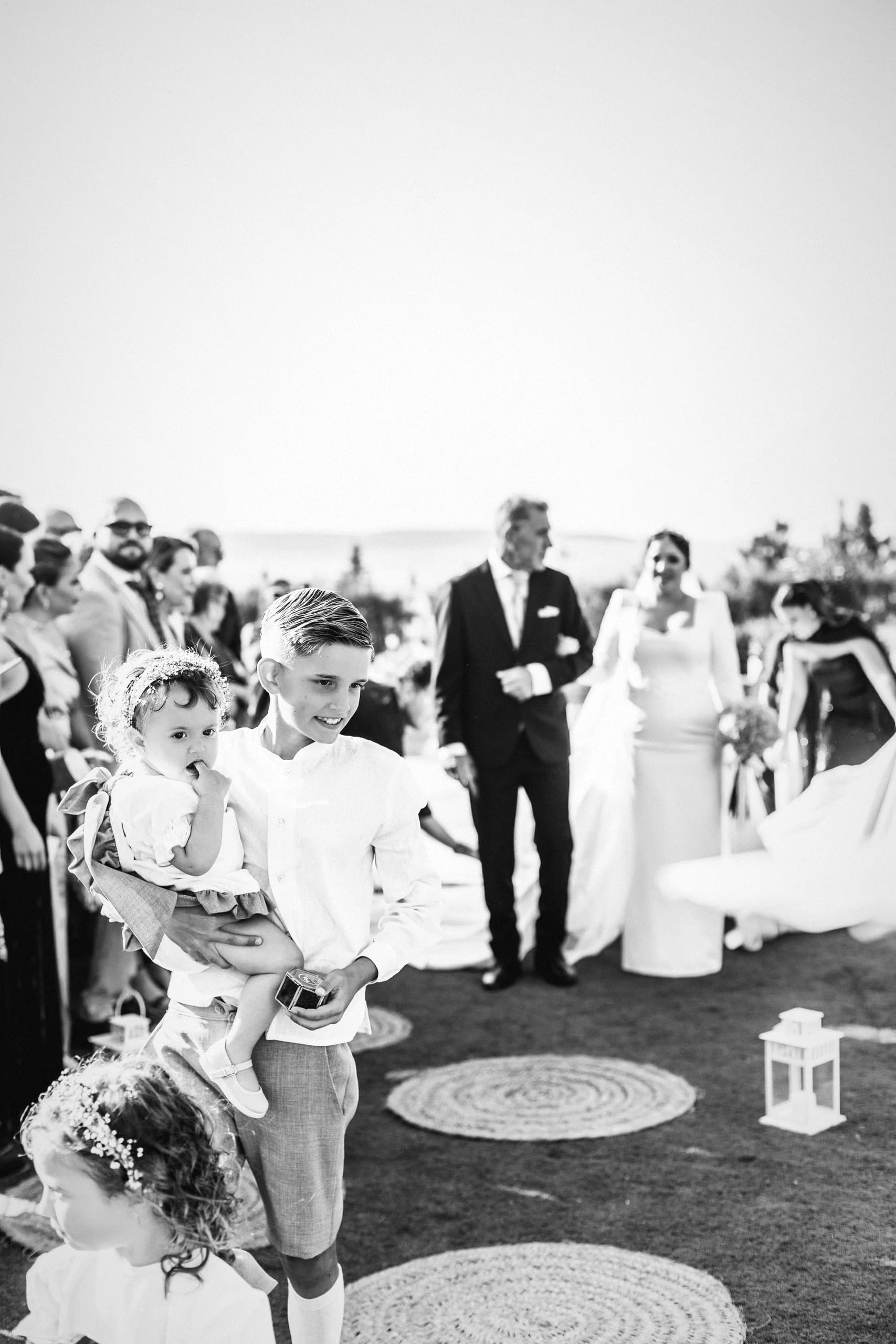 Los novios en el cóctel, entre las mesas altas, en blanco y negro