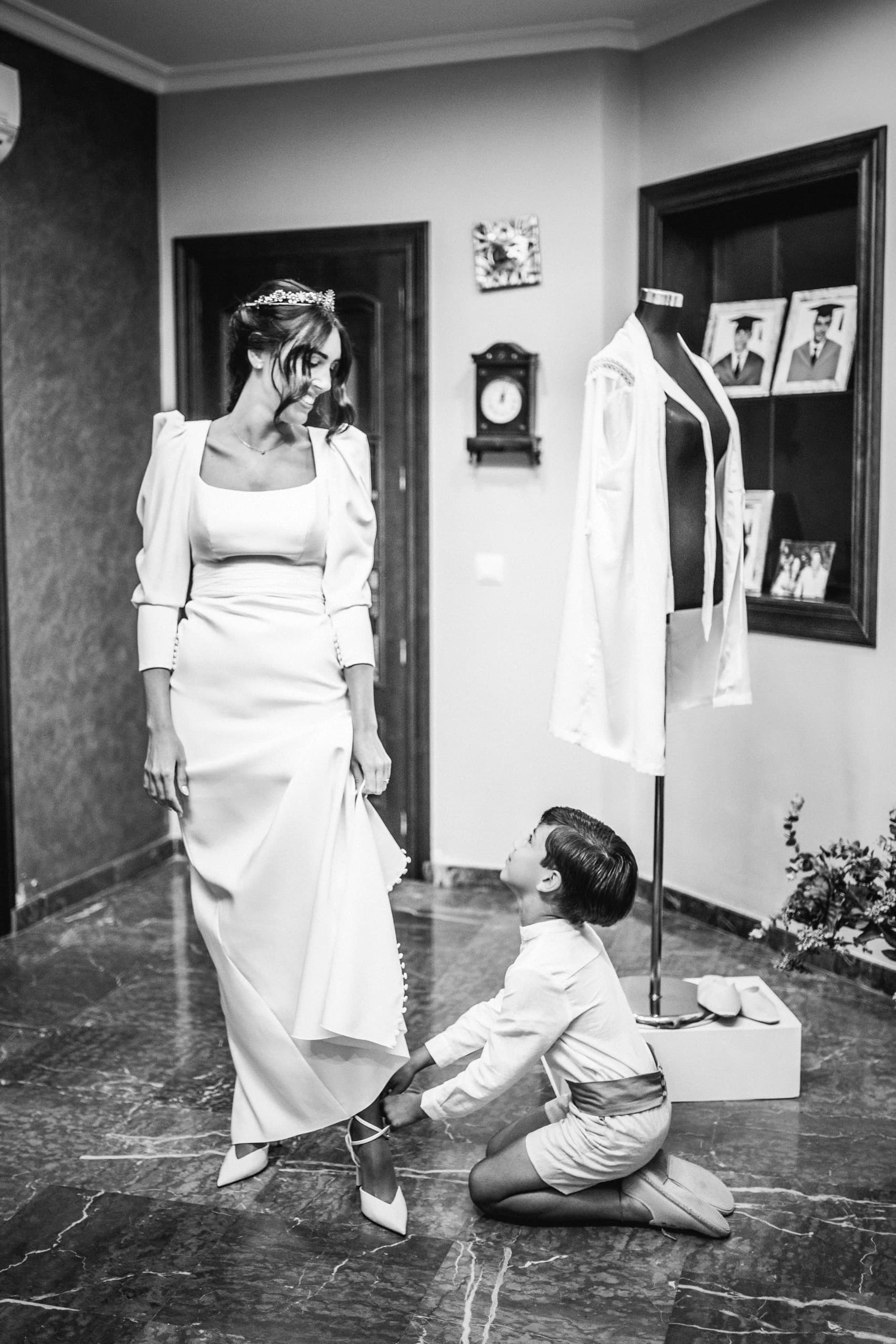 La novia poniéndose los zapatos con la ayuda de su hermano, en blanco y negro