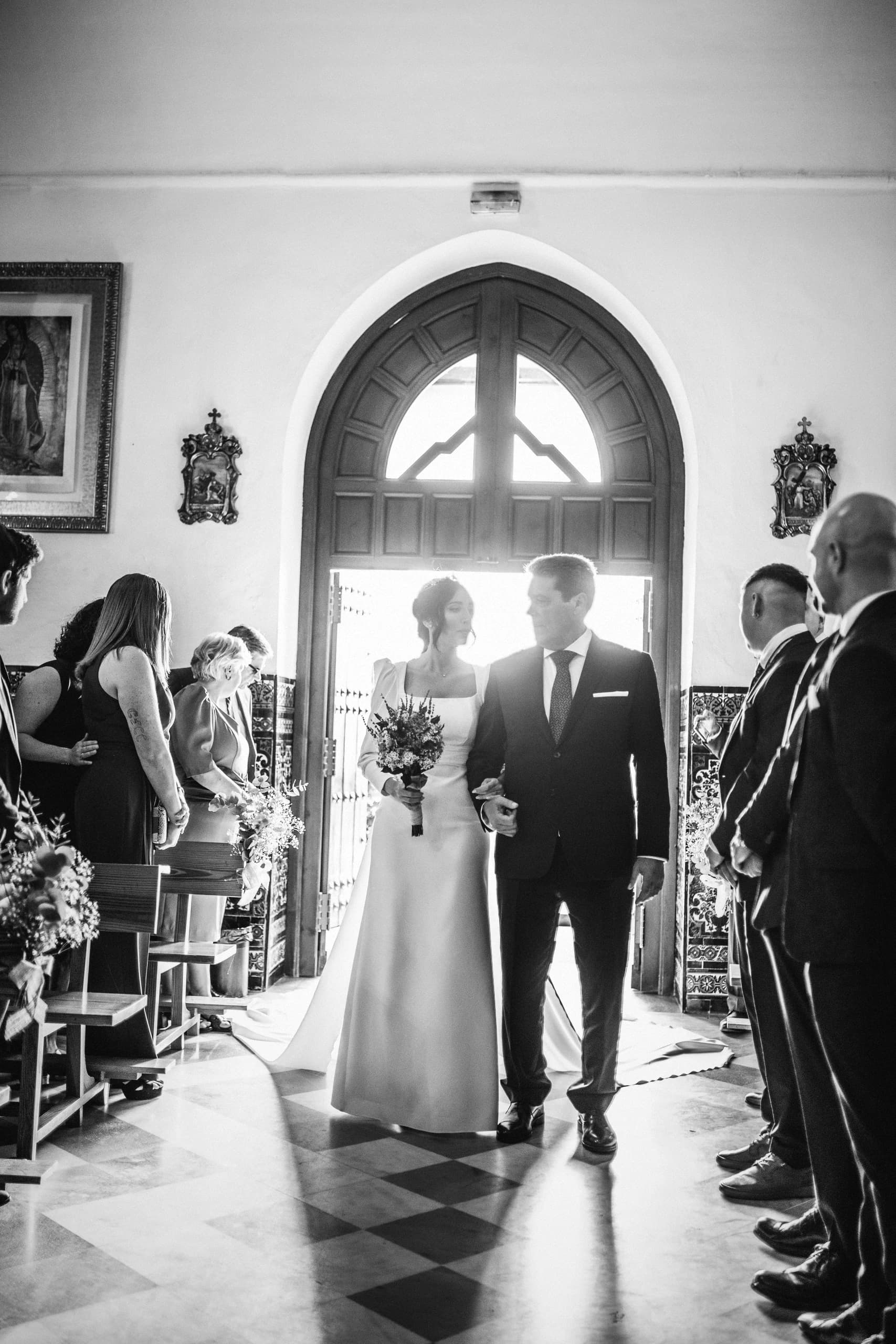 La novia entrando en la iglesia del brazo de su padre, en blanco y negro