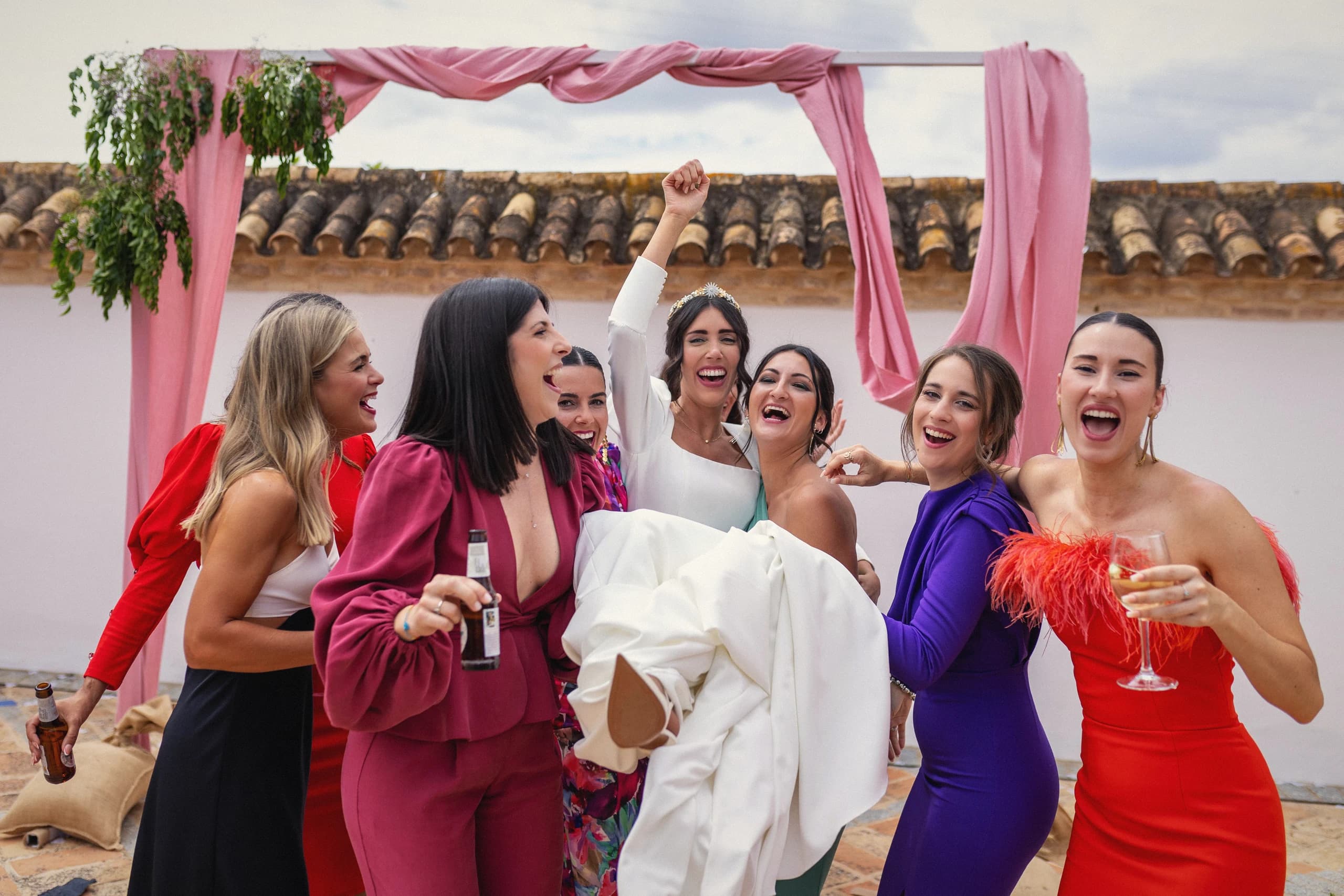 La novia con sus amigas bajo las telas rosas del patio