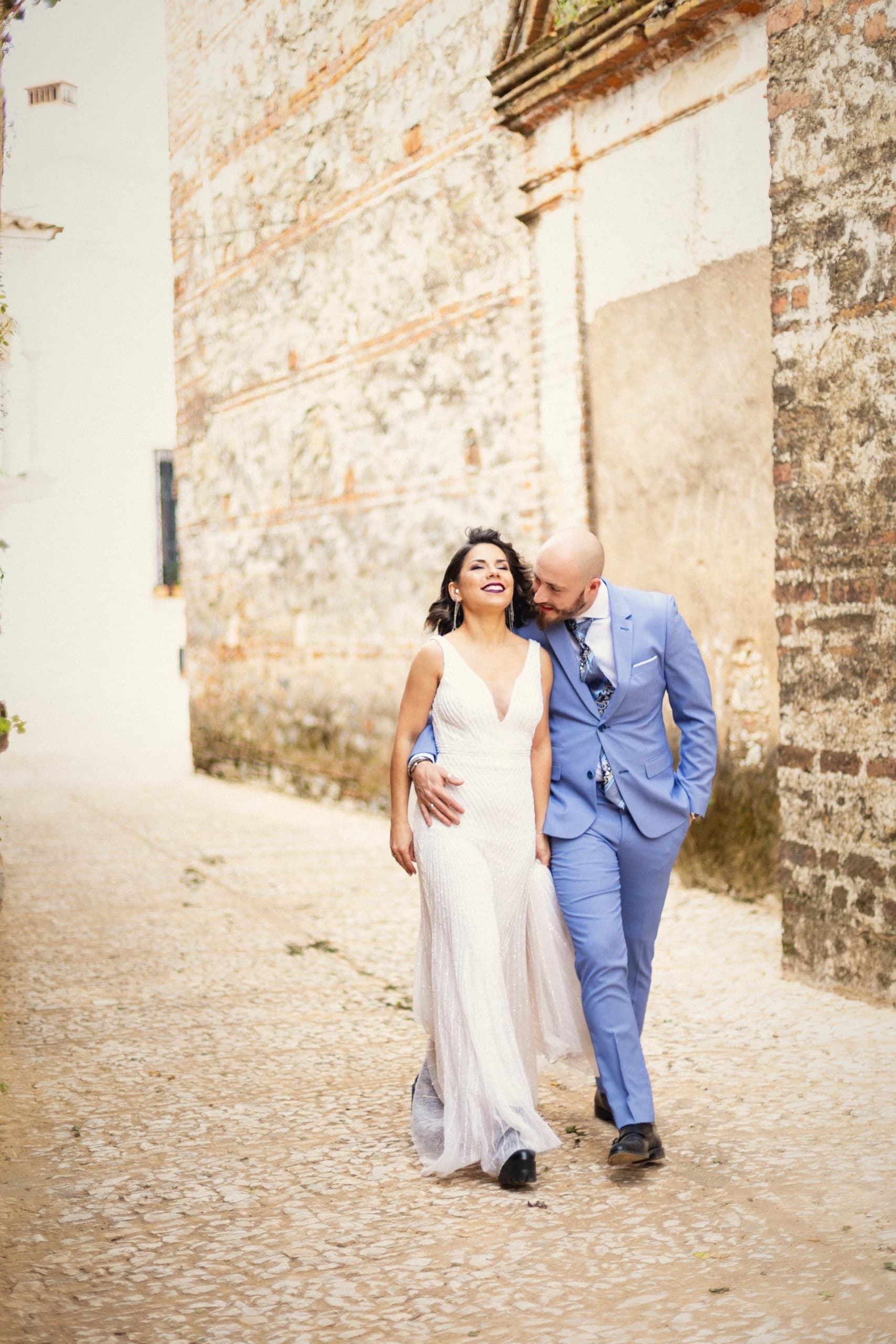 Los novios paseando de la mano por la calle empedrada