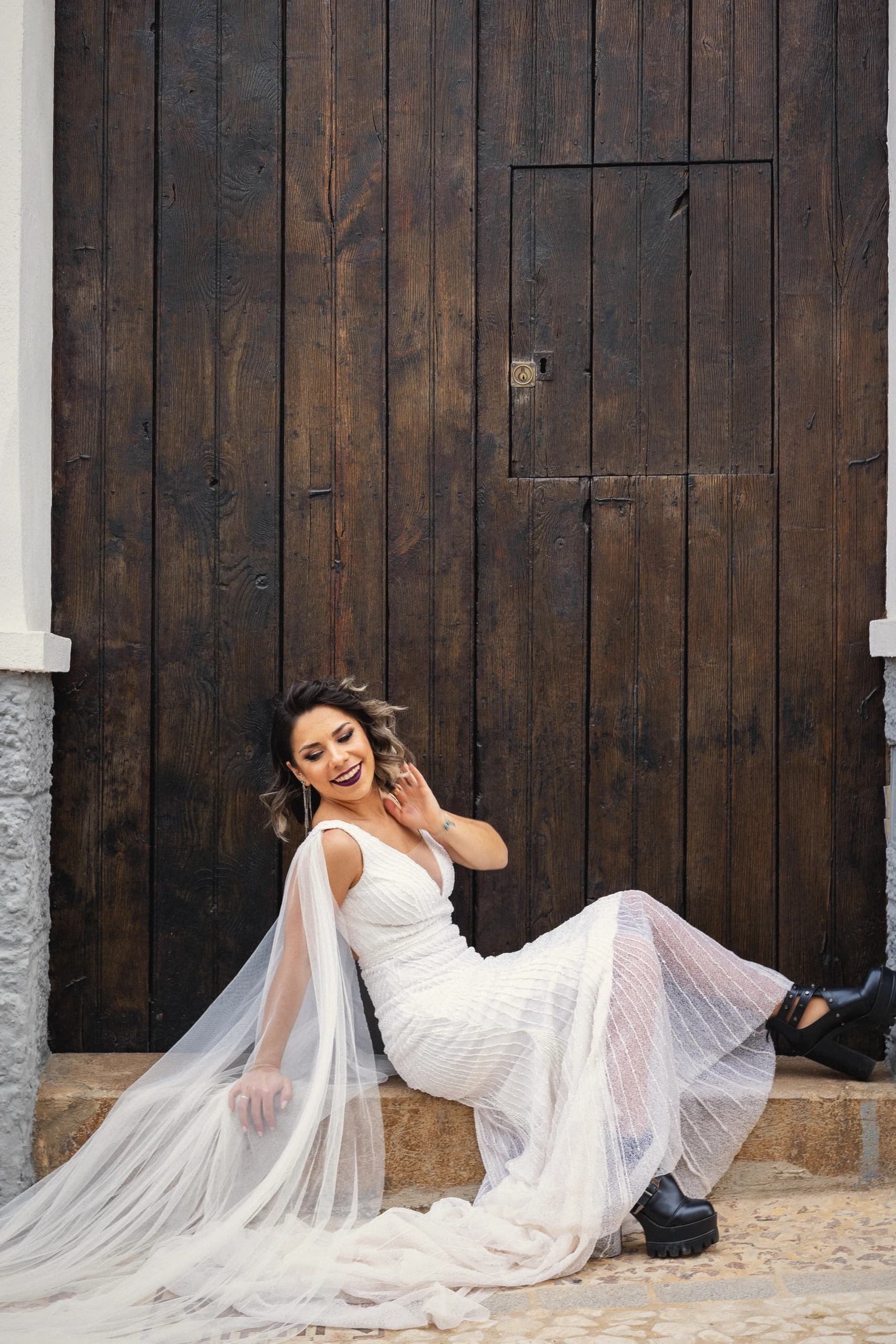 La novia recostada ante un portón de madera oscura