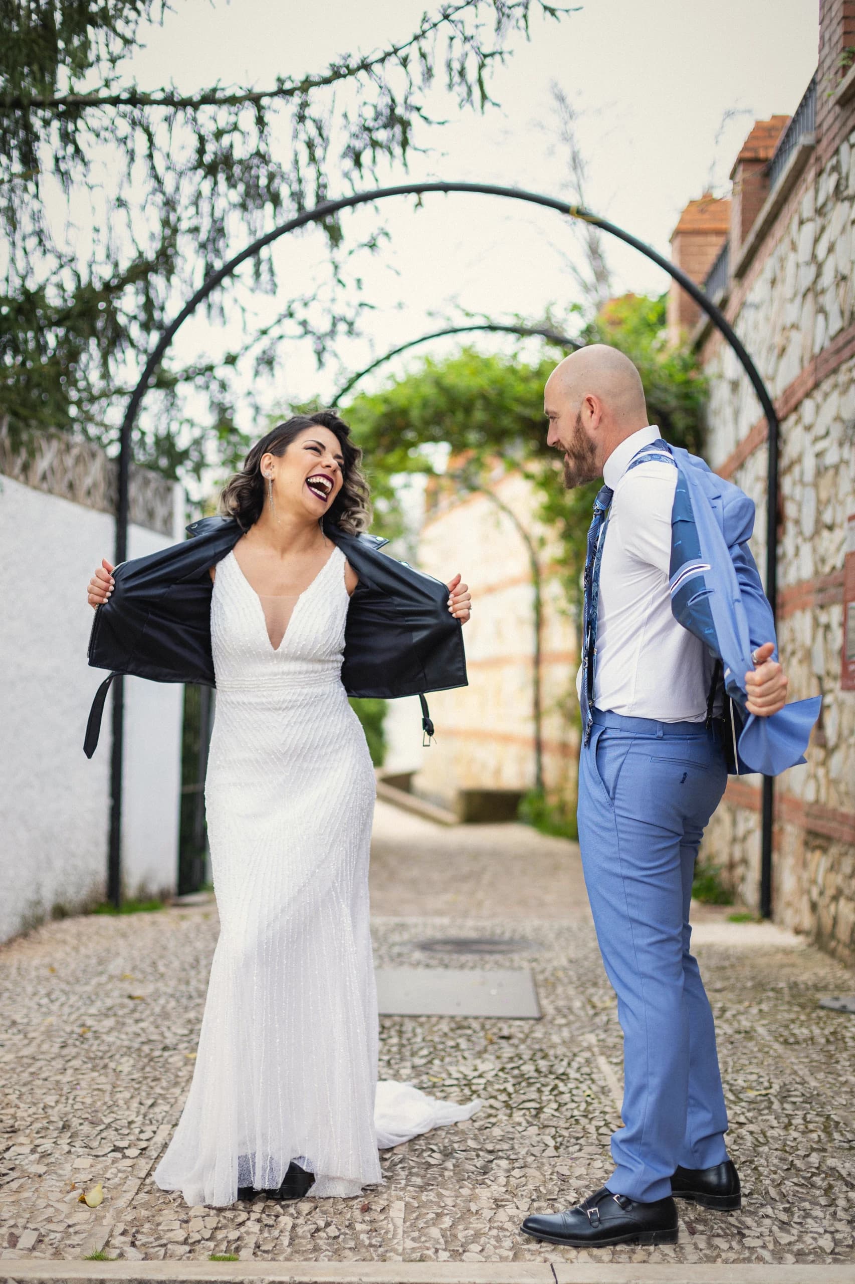 La novia riéndose con la chaqueta de cuero bajo el arco de hierro
