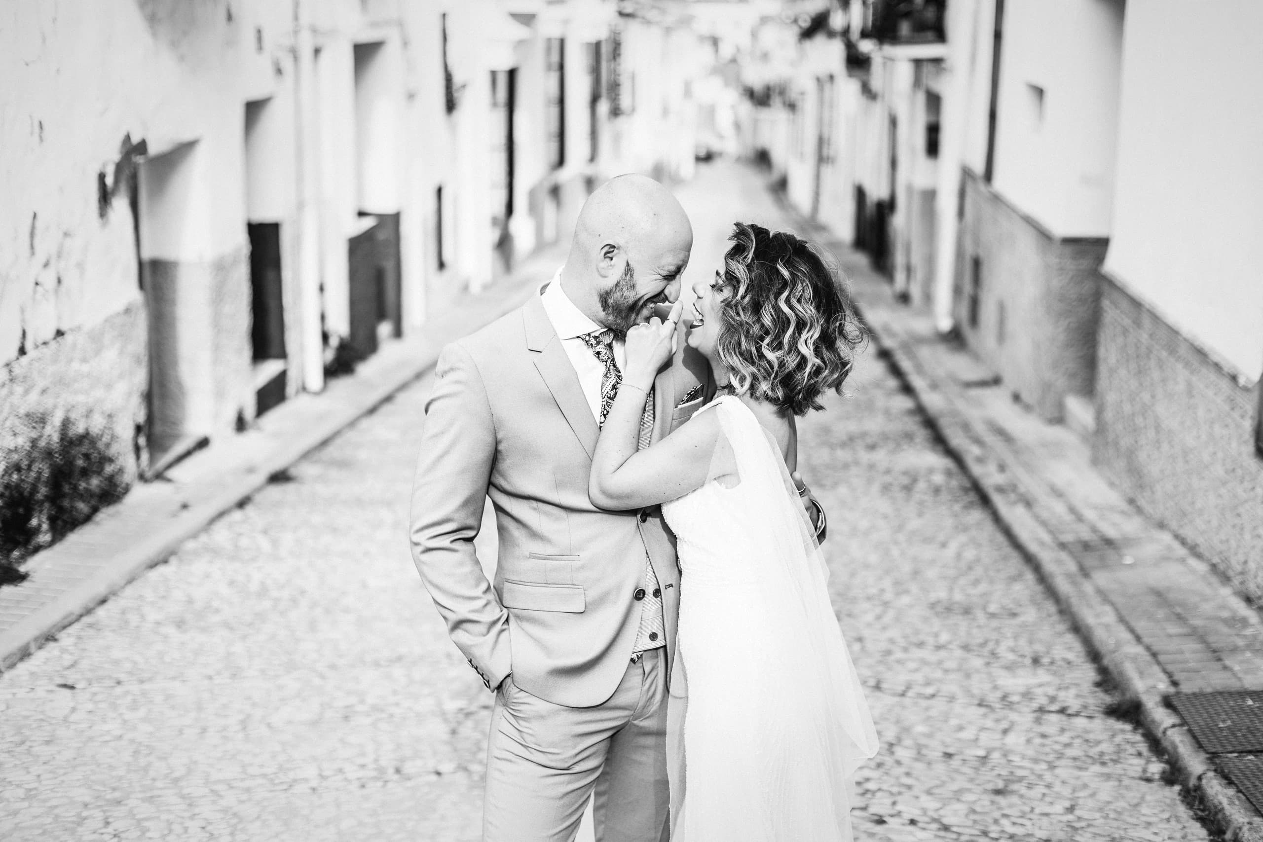 Un beso en mitad de la calle empedrada, entre las fachadas encaladas, en blanco y negro
