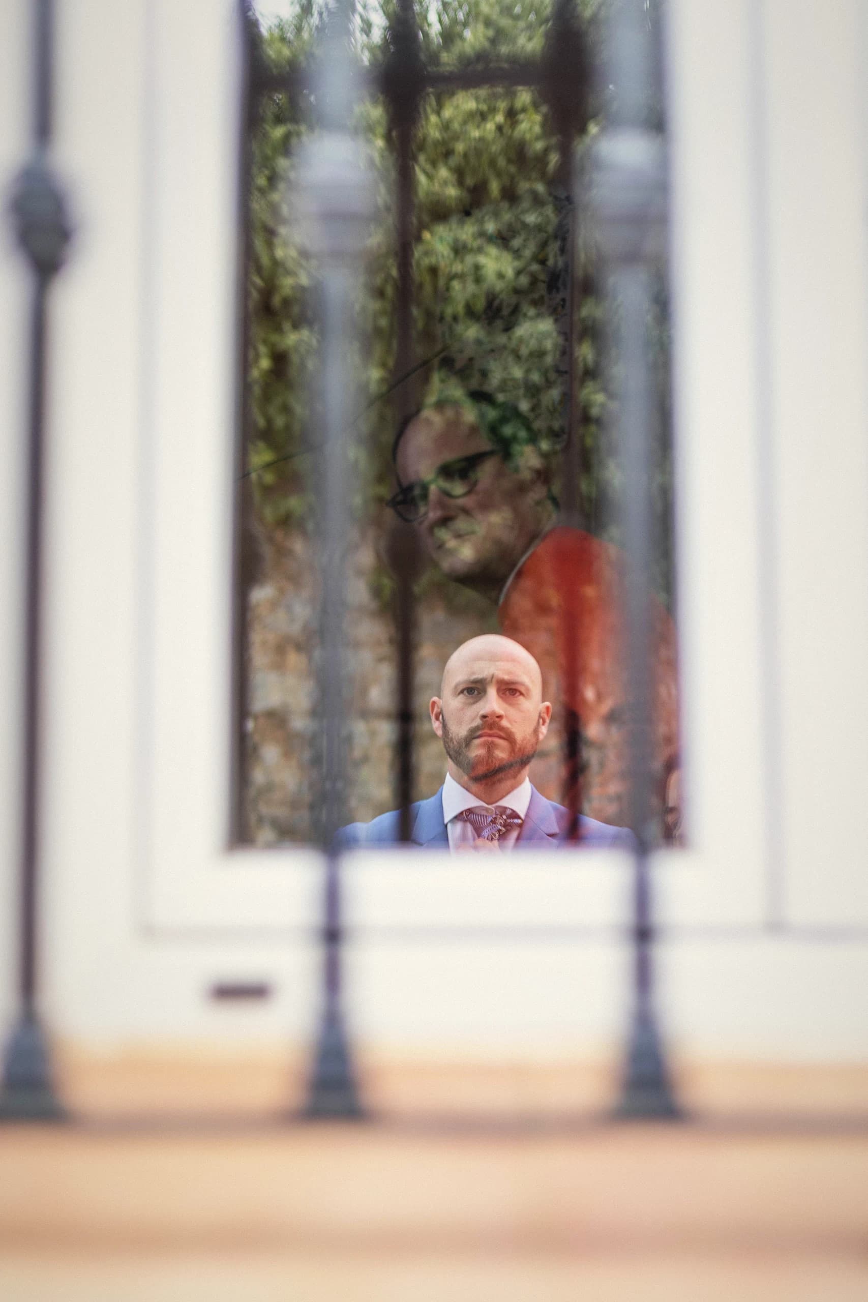 Retrato de él visto a través de una reja, con los barrotes desenfocados en primer plano