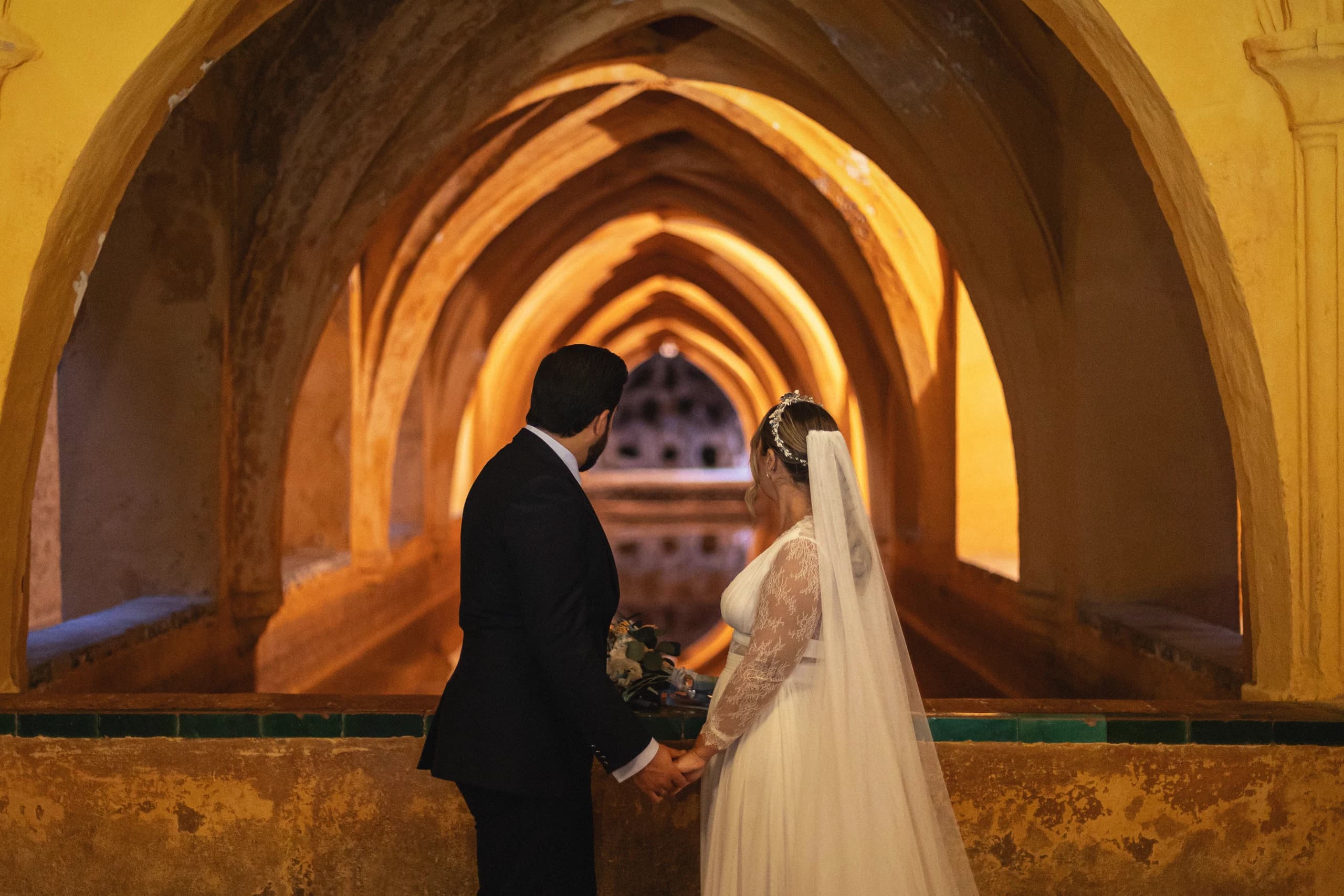 Los novios de la mano bajo las bóvedas de los baños de Doña María de Padilla