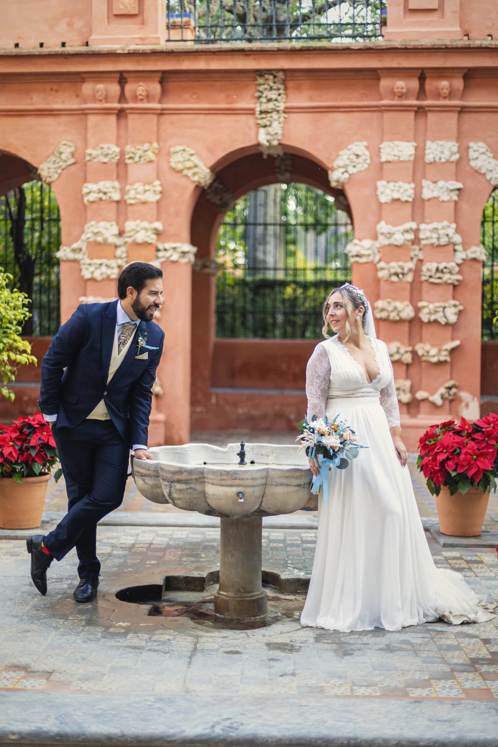 Los novios junto a la fuente del patio, con flores de pascua