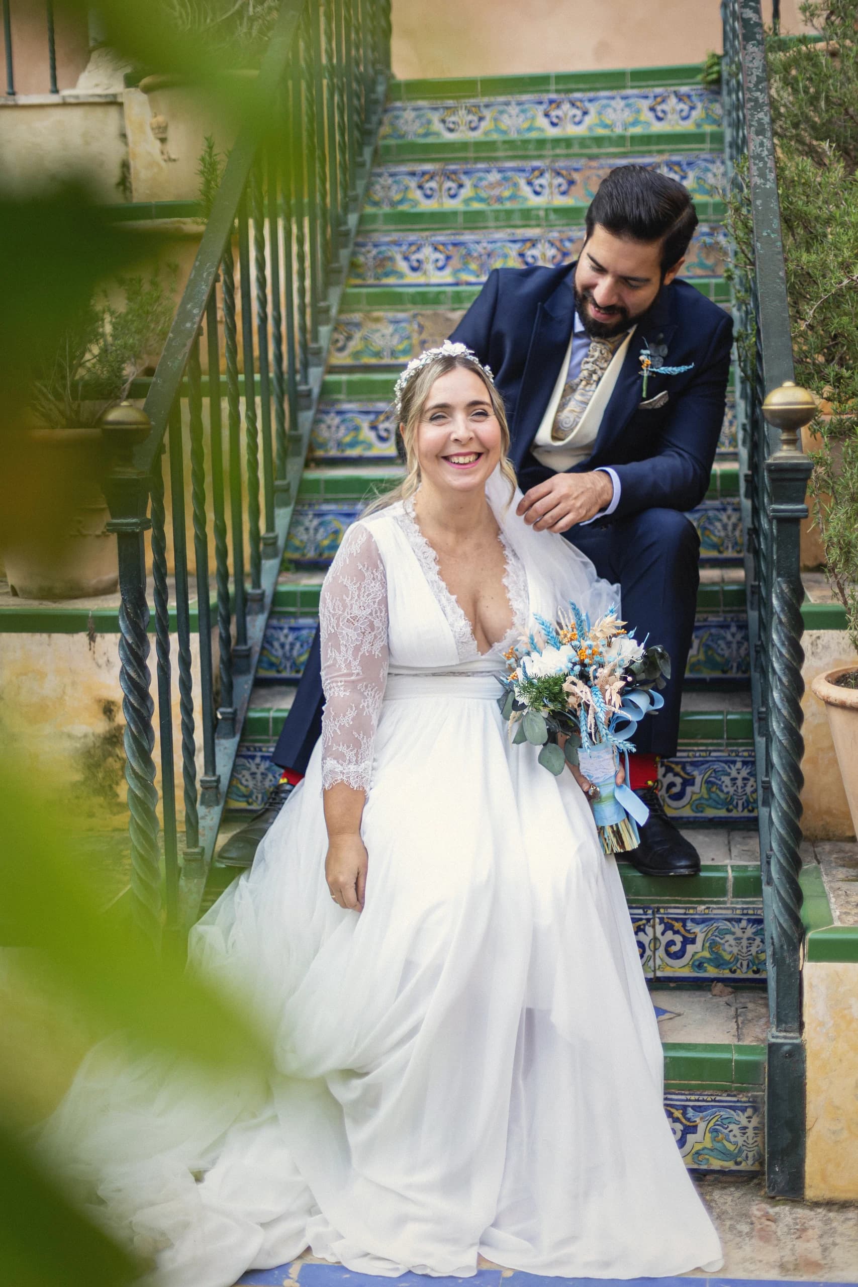Los novios sentados en la escalera de azulejos del jardín