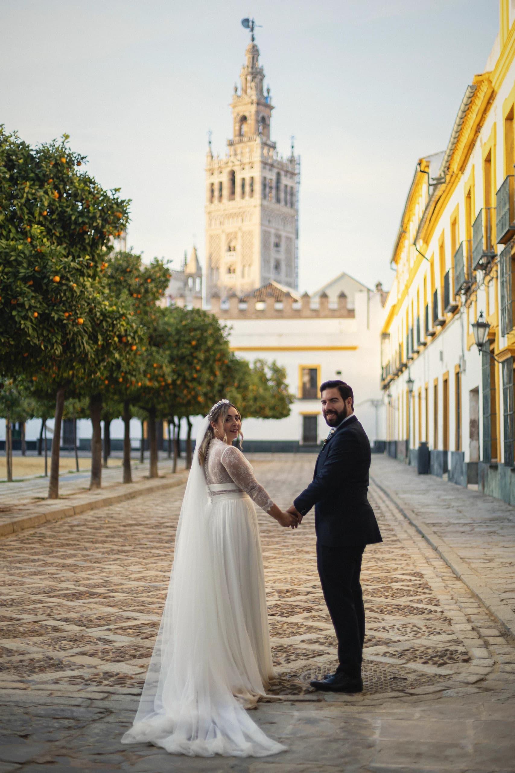 Los novios de la mano en el Patio de Banderas con la Giralda detrás