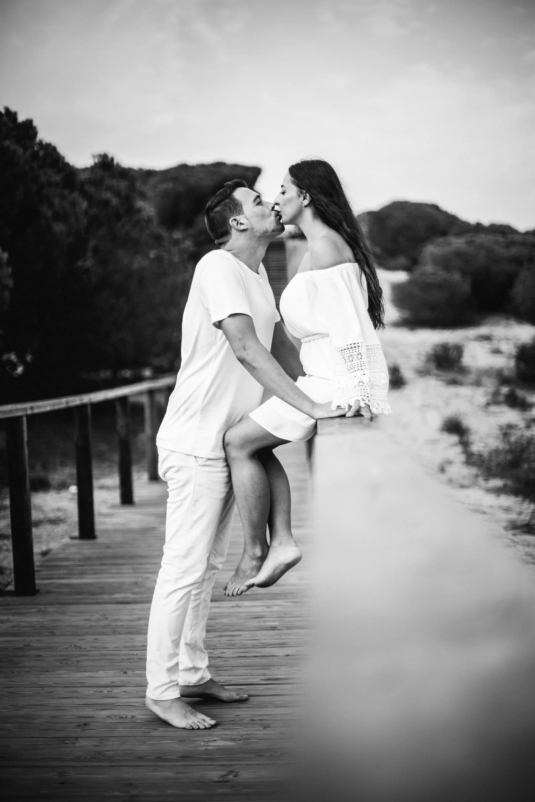 Beso de puntillas en la pasarela de madera, en blanco y negro