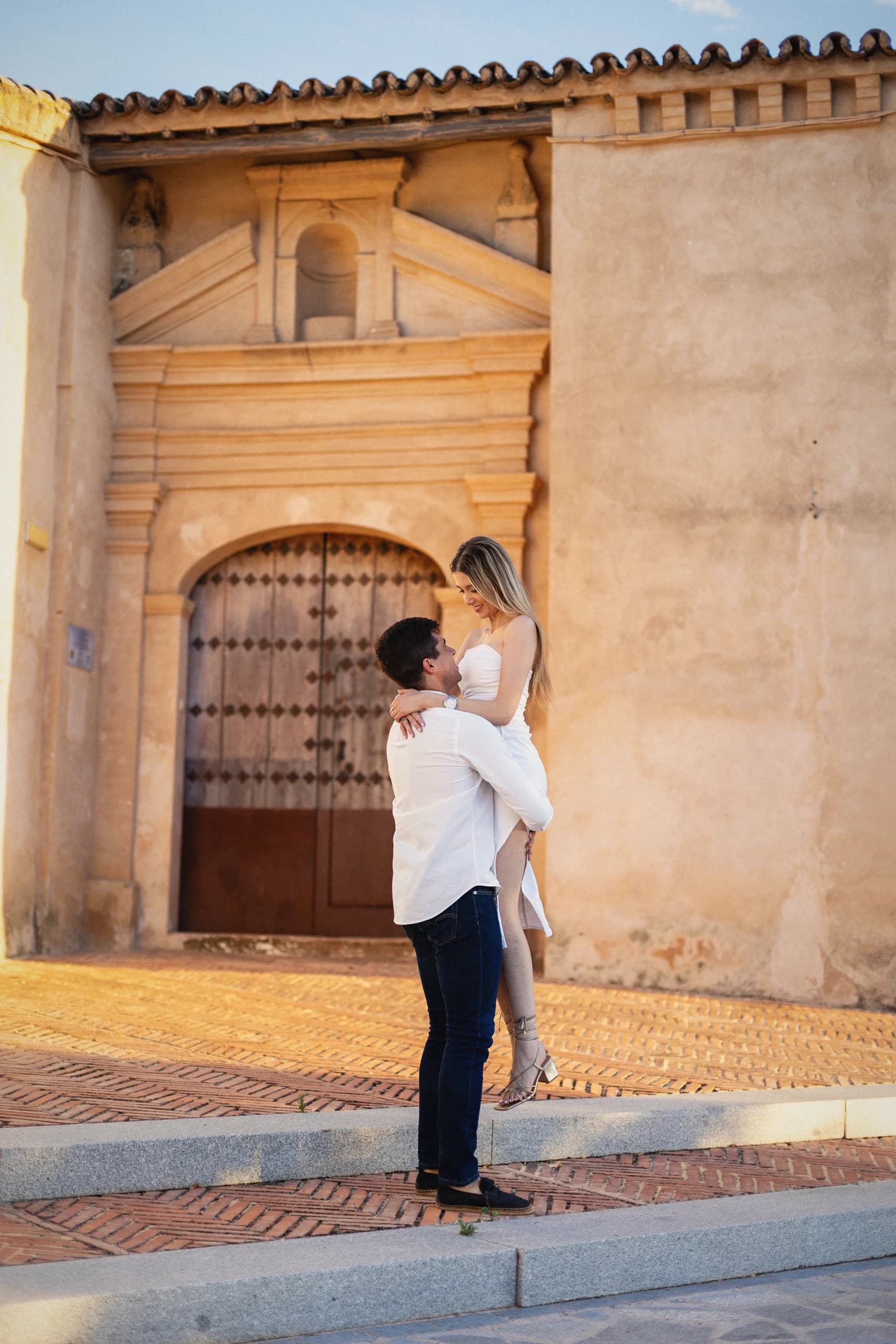 La pareja abrazada en la esquina de la iglesia, a la luz dorada