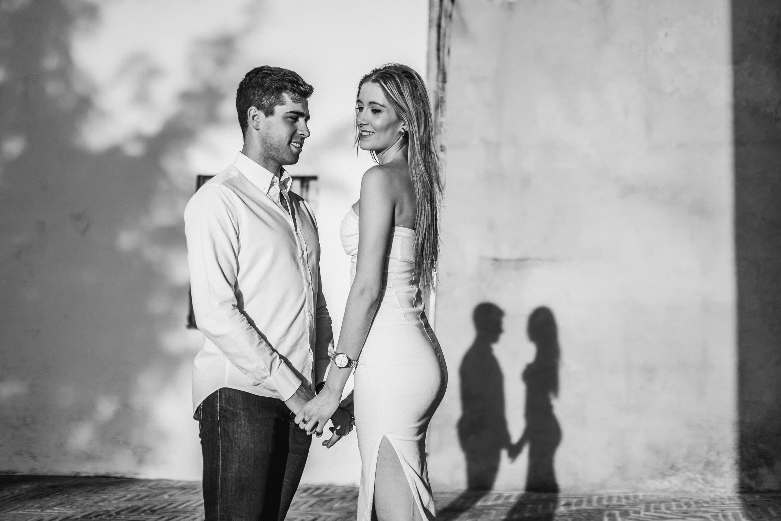 Sus sombras dadas la mano proyectadas sobre la pared encalada, en blanco y negro